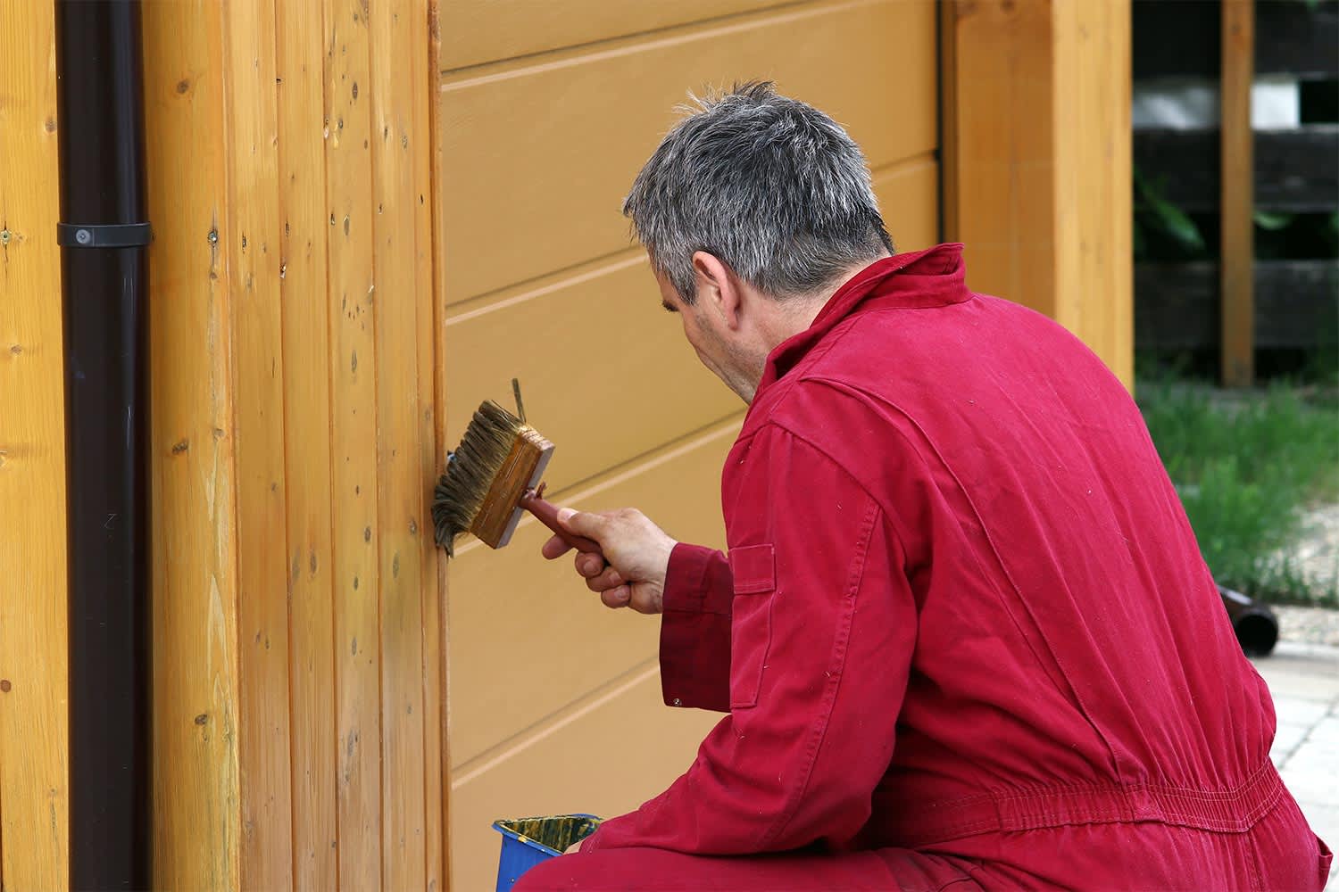 man using brush to paint garage door