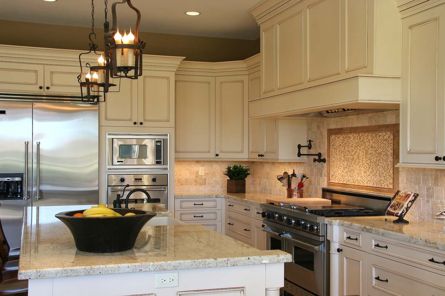Luxury kitchen with stone and tile backsplash, white cabinets and kitchen island