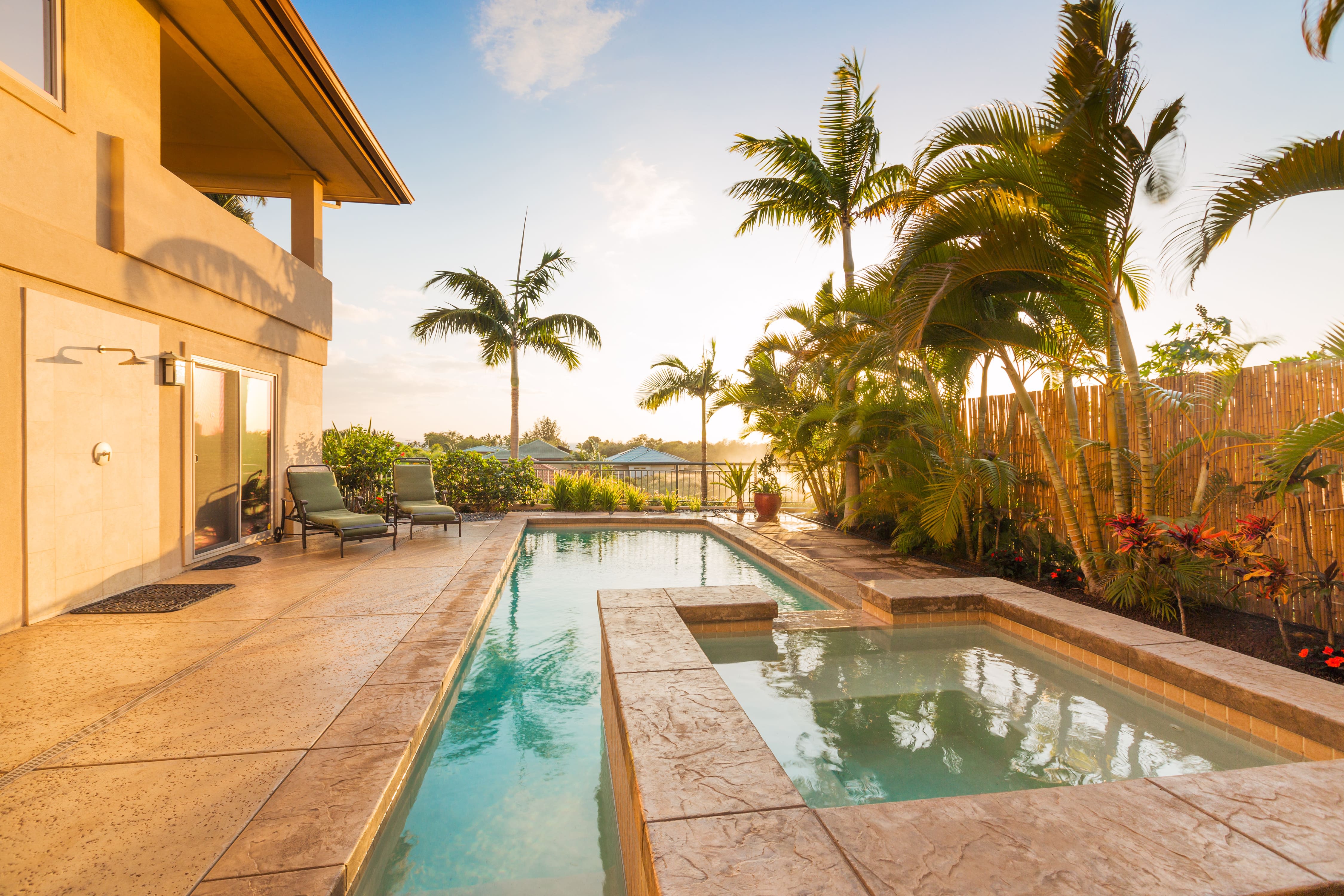 The backyard of a modern looking home with a stone hot tub and pool