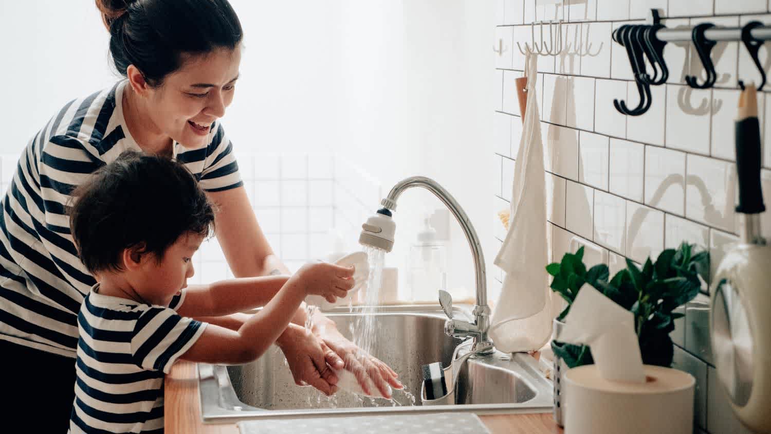 A mother with her kid doing the dishes in the kitchen