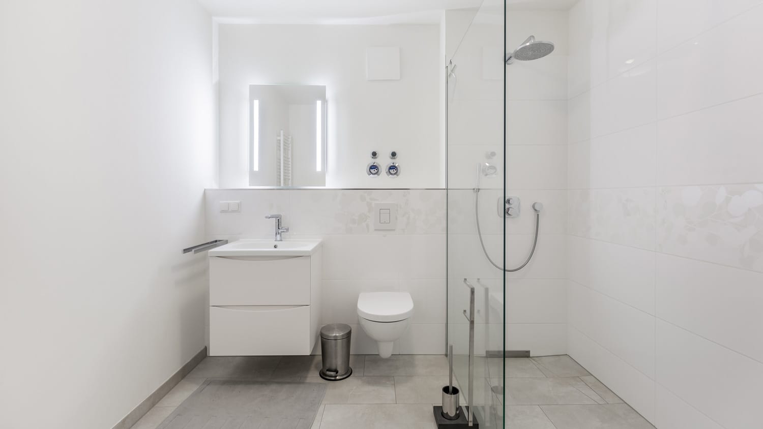 A white minimalistic bathroom with a glass shower cabin