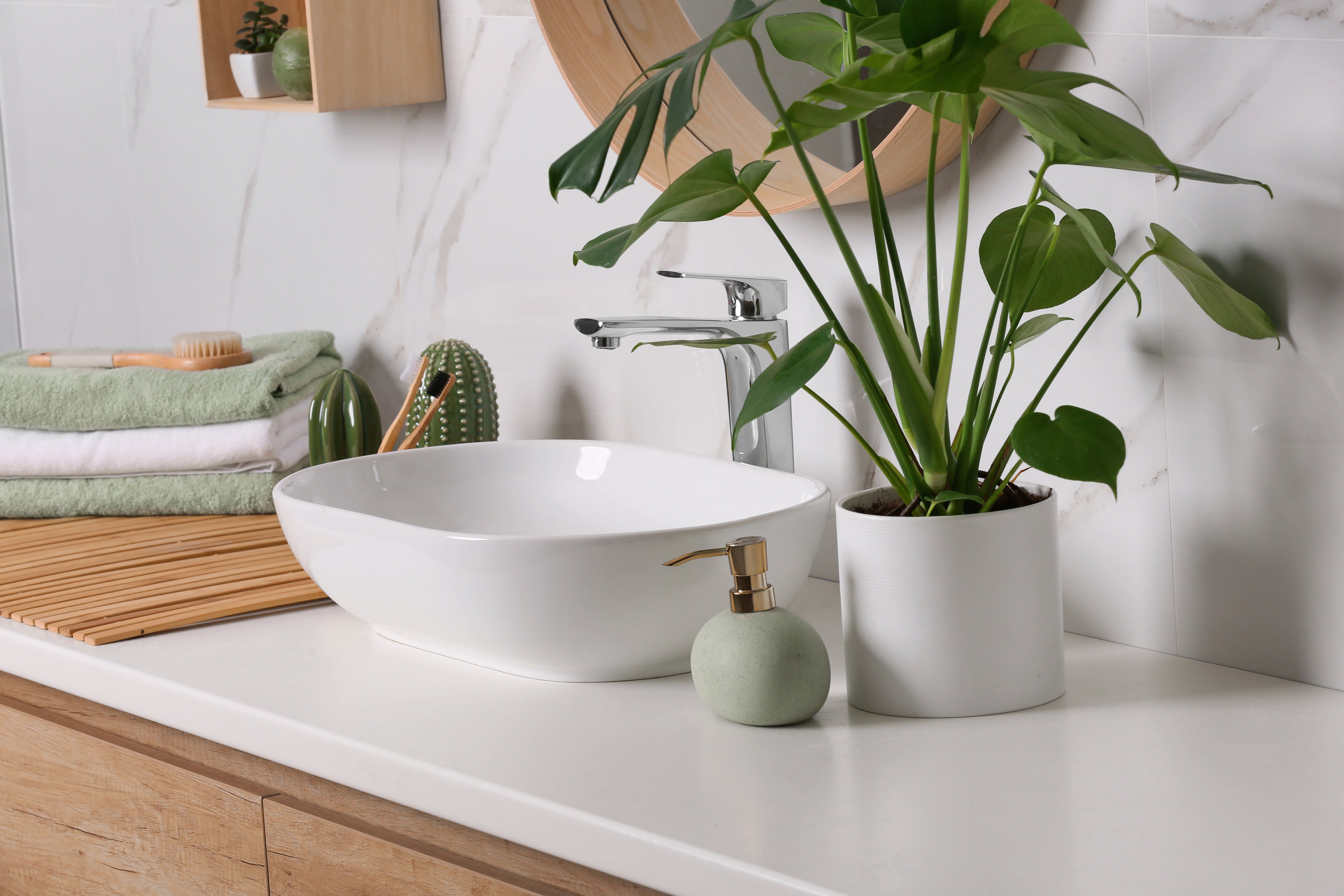 Modern bathroom with a marble backsplash, wooden vanity, and white vessel sink