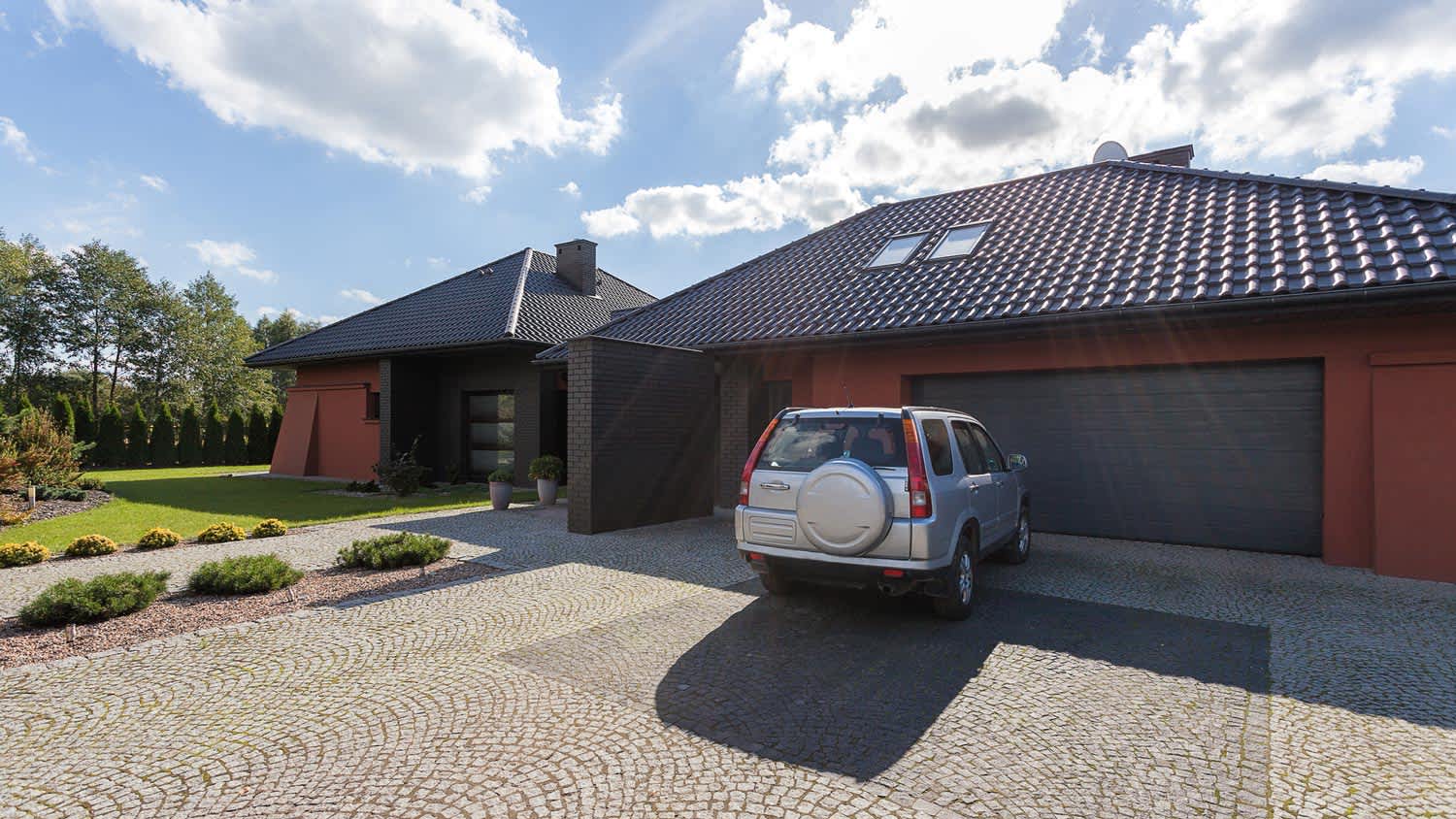 A car parked in the driveway in front of a garage door