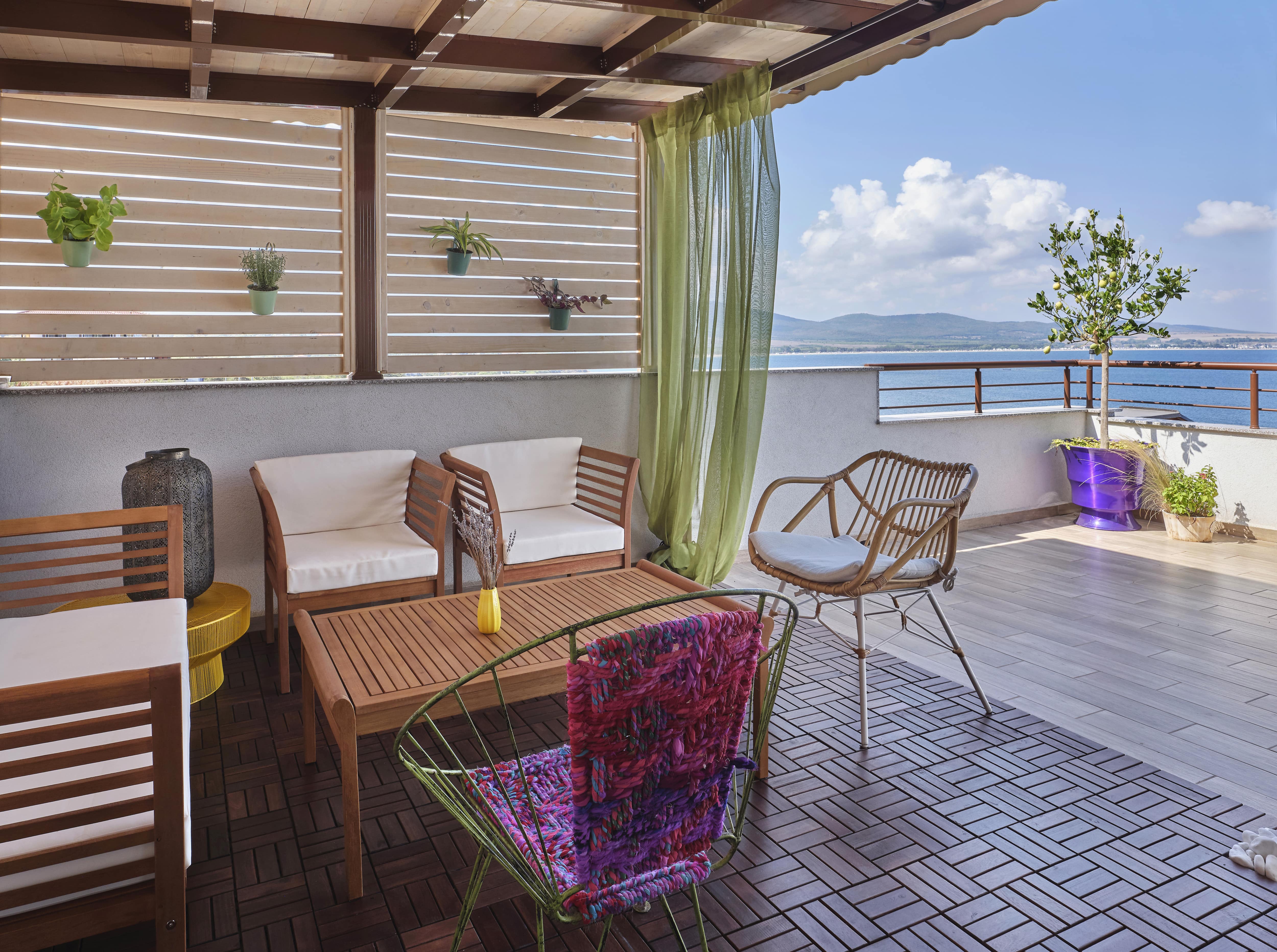 Covered patio with green curtains with water views.