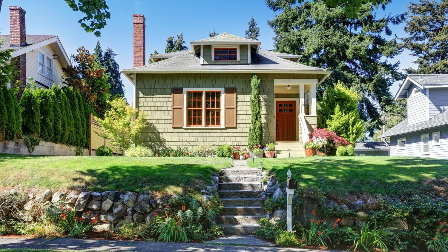 A cute green craftsman house with a nice garden