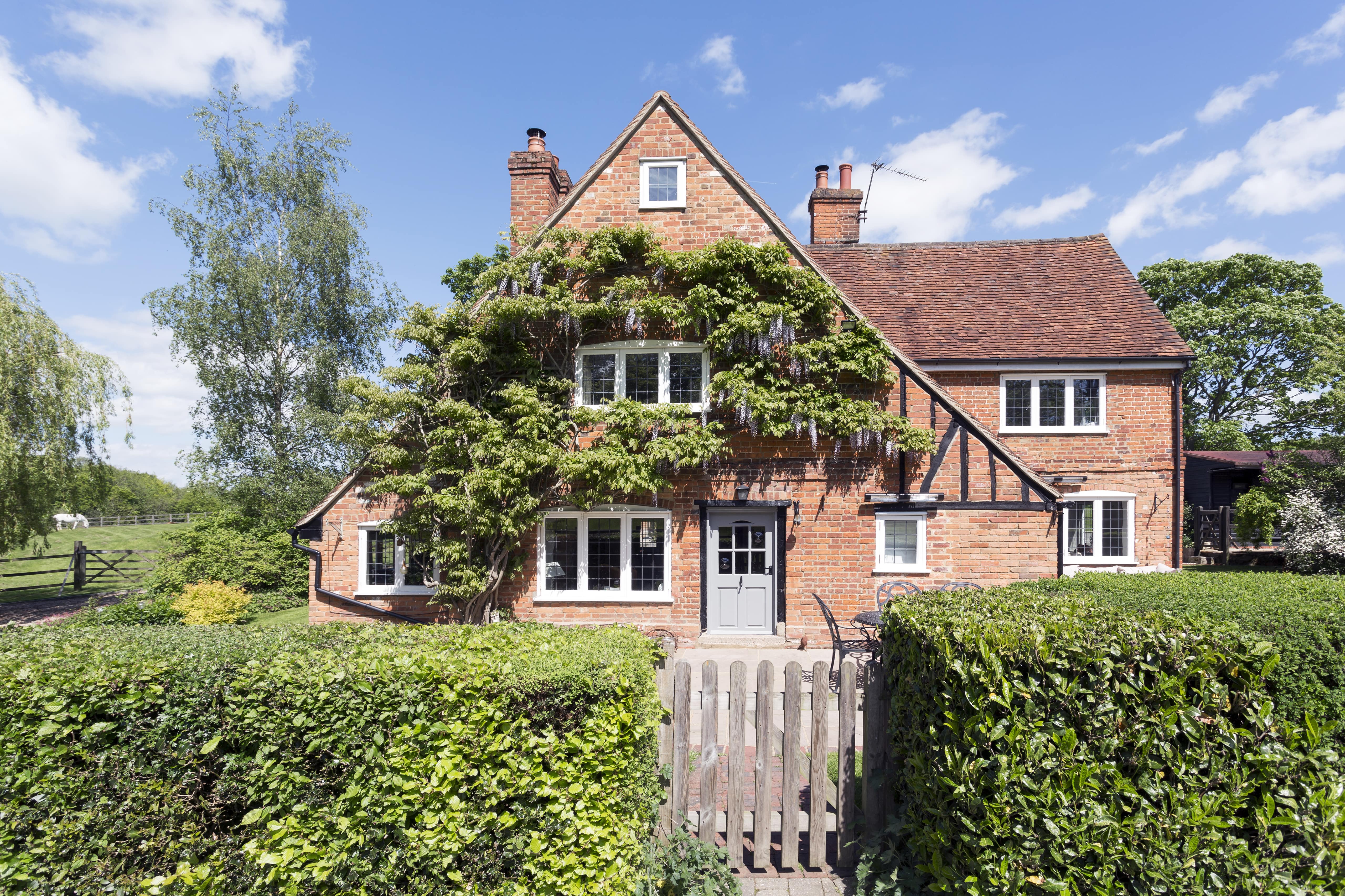 A lovely brick home with a hedge fence in the front yard