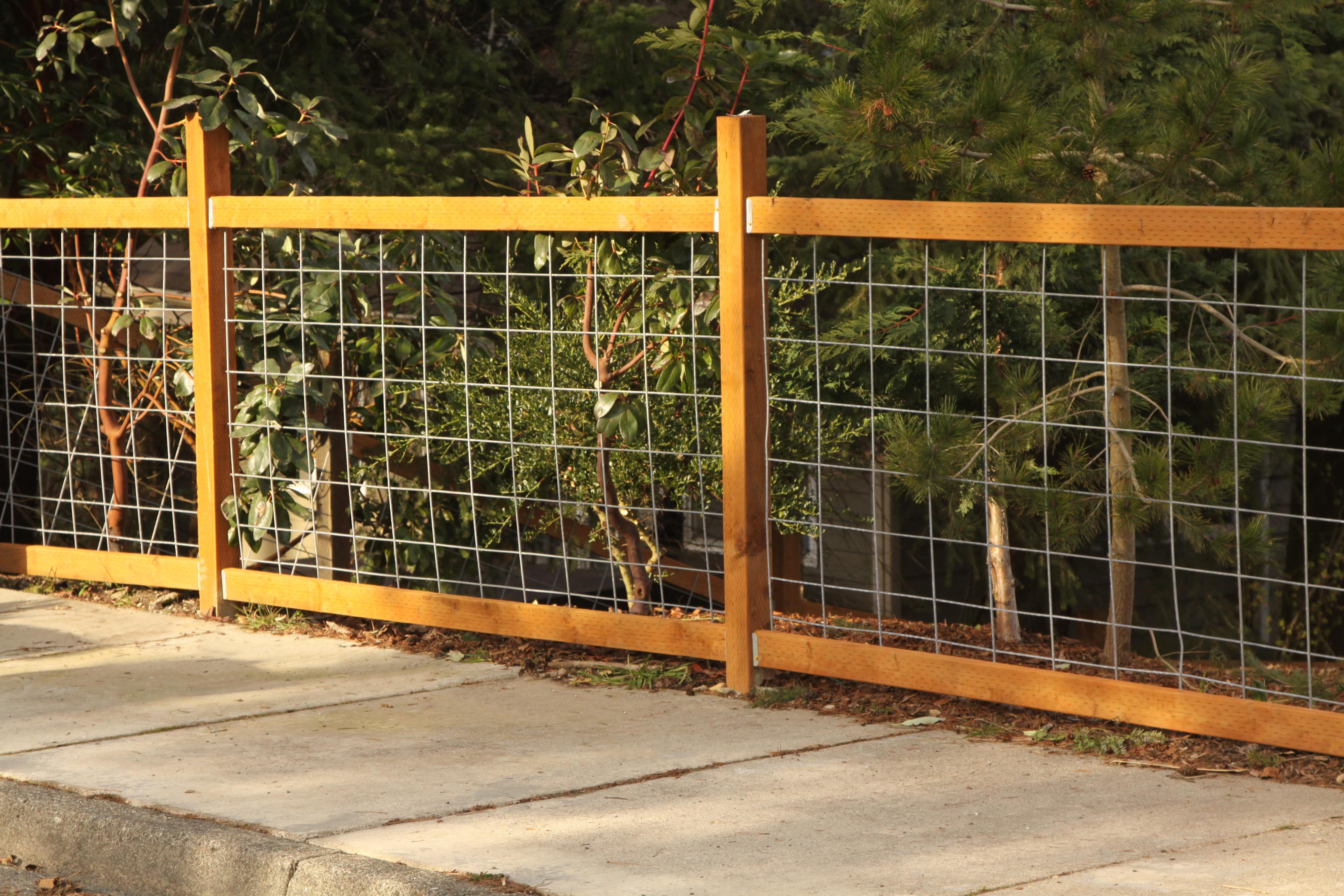 A close up image of a light wood colored wood and wire fence