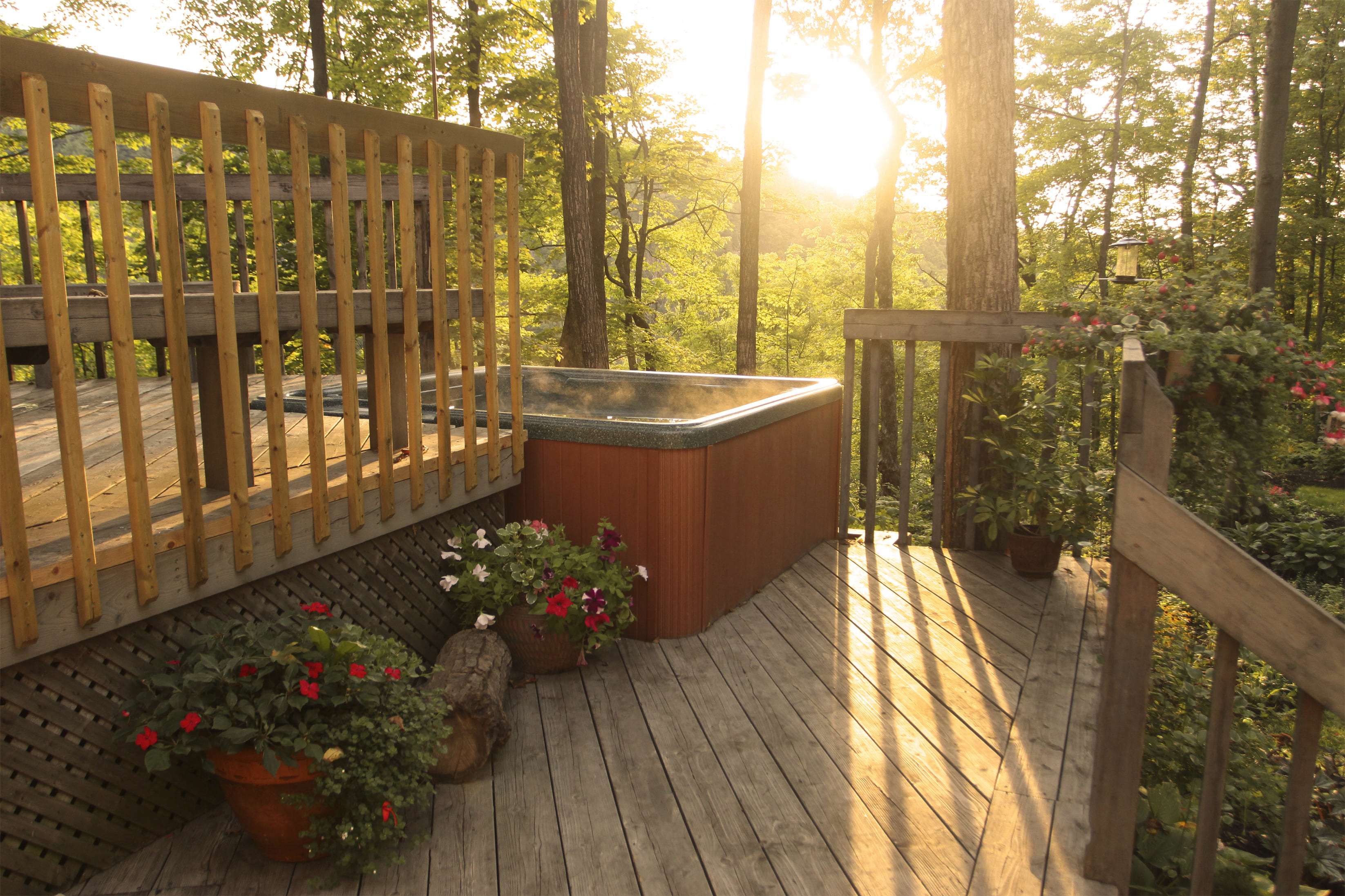 A deck with multiple levels and a hot tub surrounded by trees