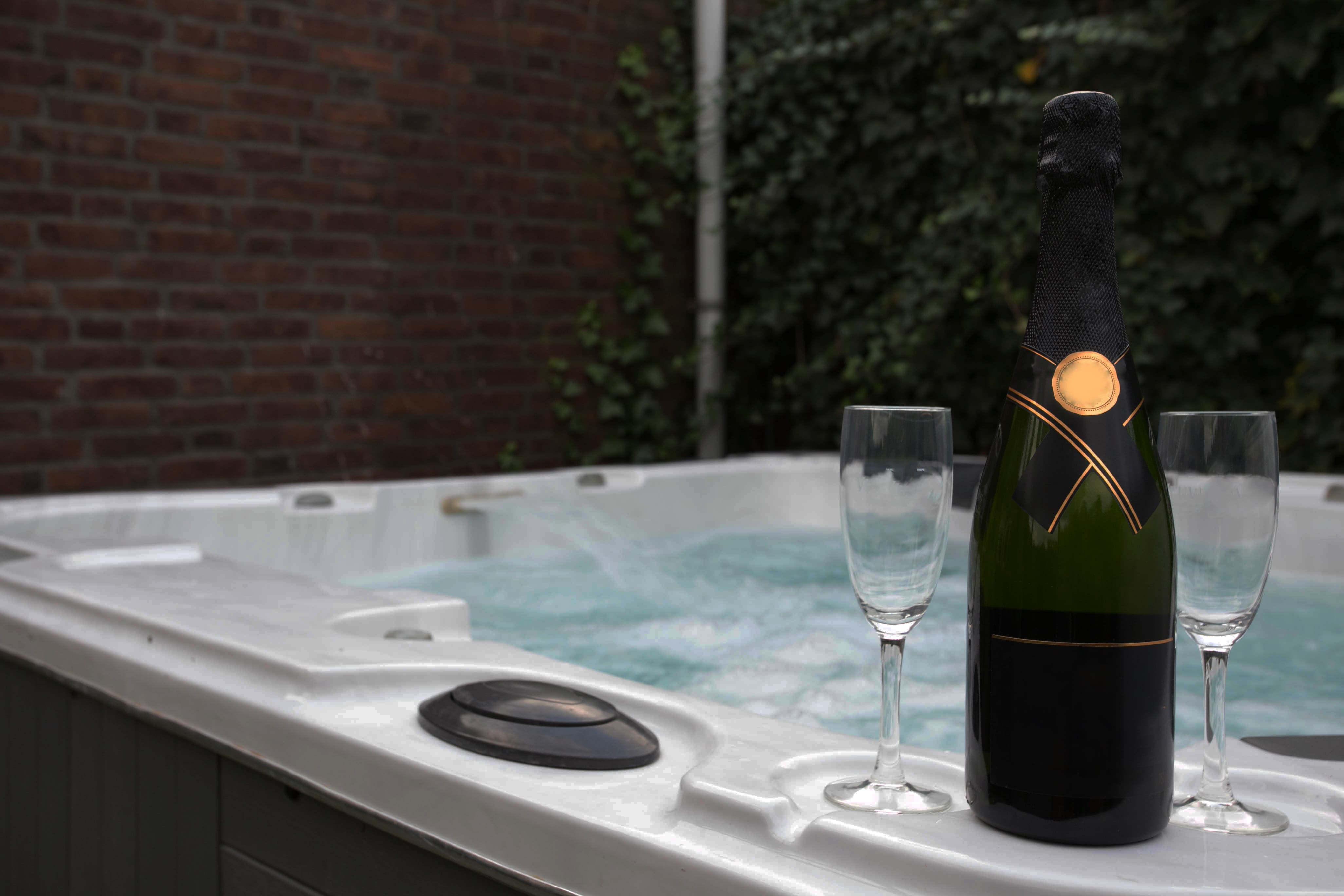 Close up image of a hot tub with a bottle of champagne and two glasses