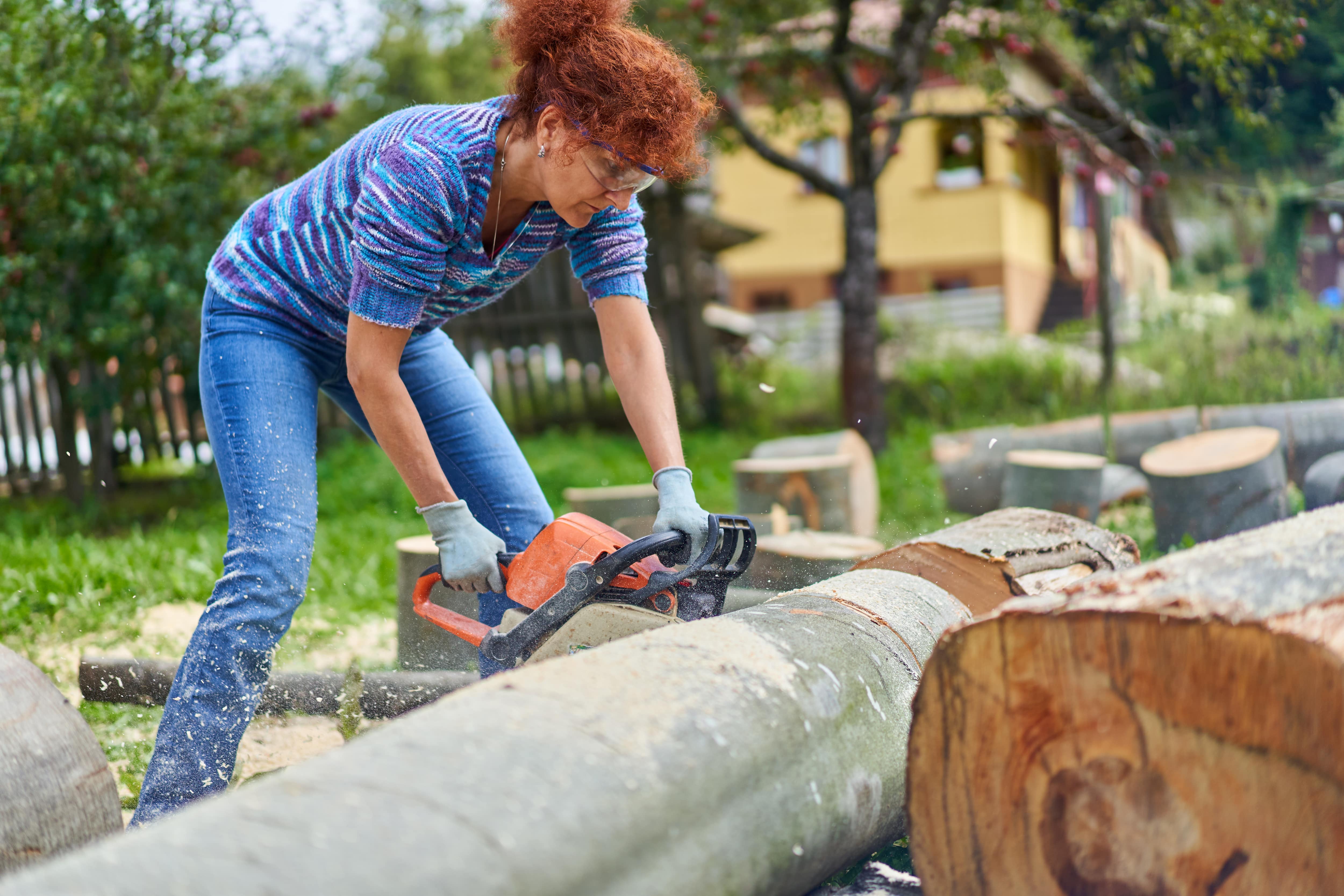 Woman using a chainsaw to cut a tree