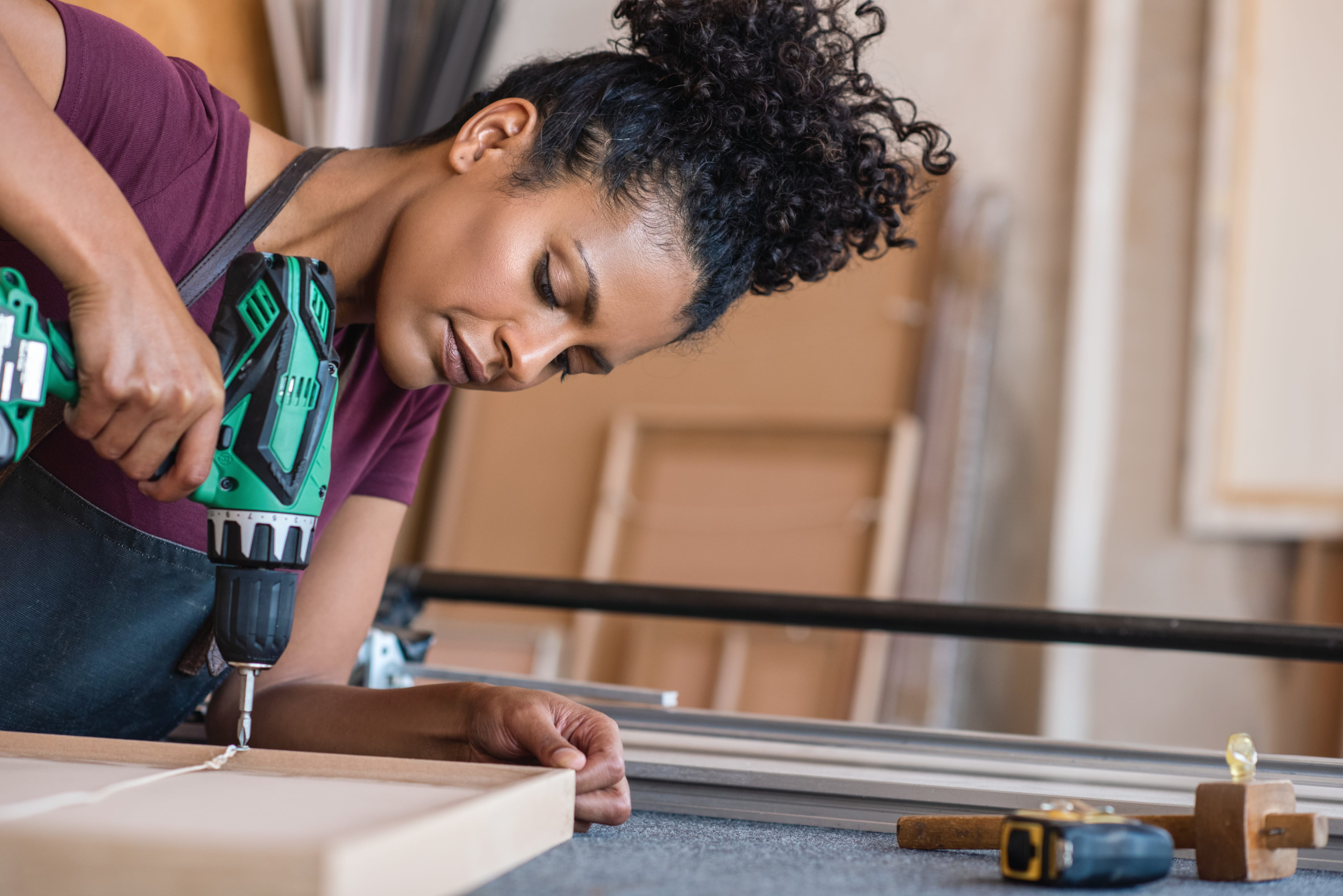 Woman using a drill in her workshop