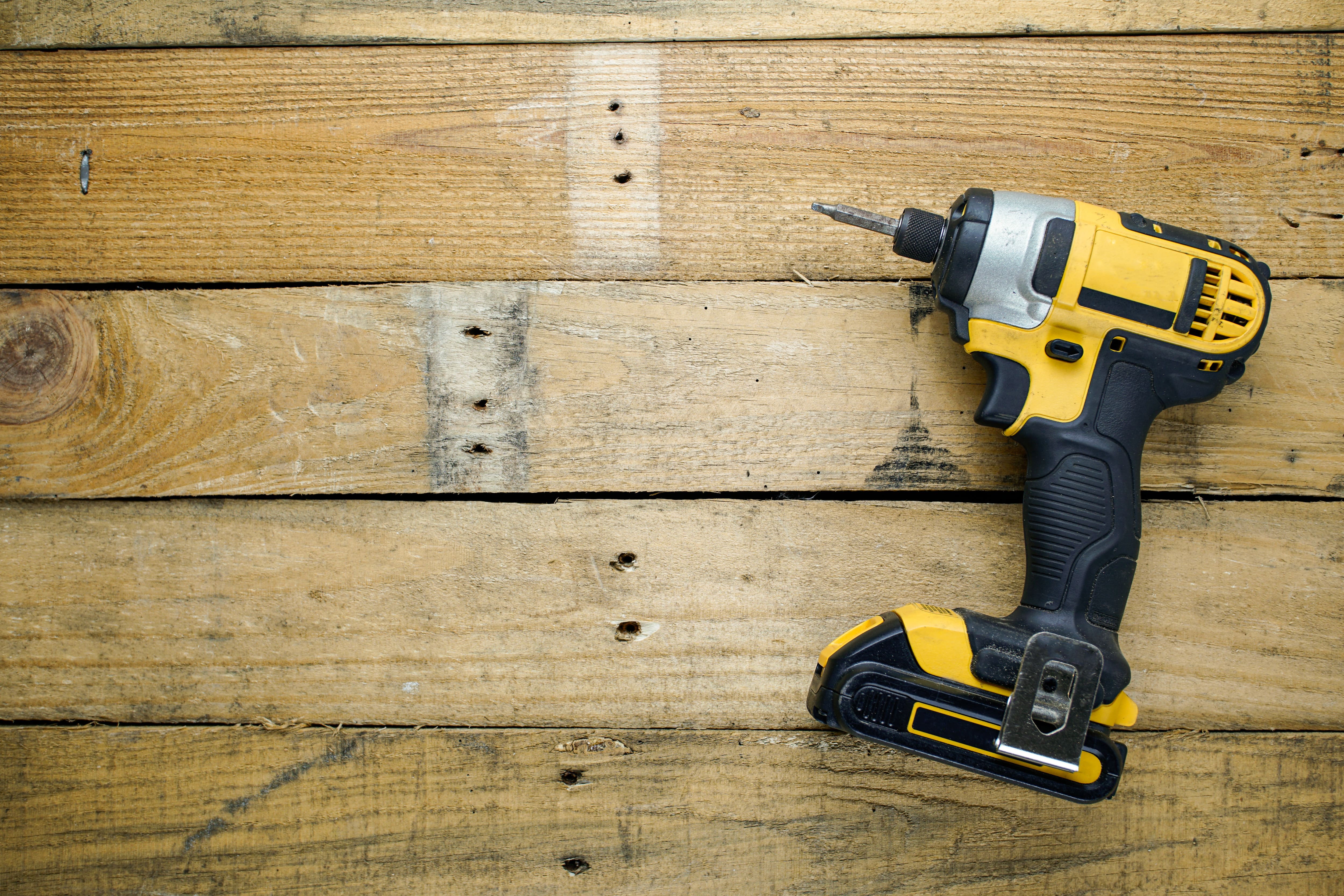 Yellow and black battery-powered impact driver sitting on a wooden table
