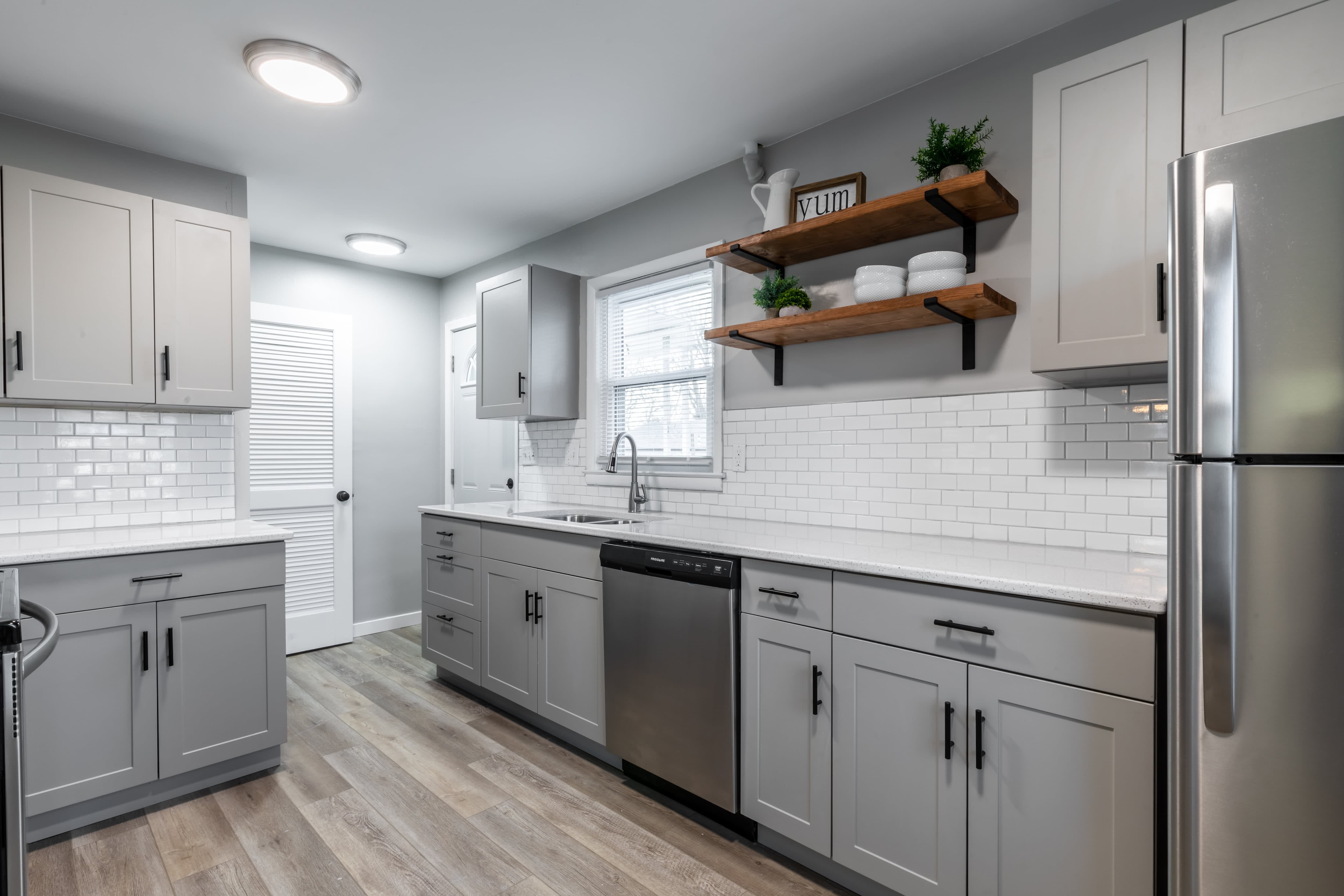 A small white kitchen with glossy white subway tile and gray cabinetry