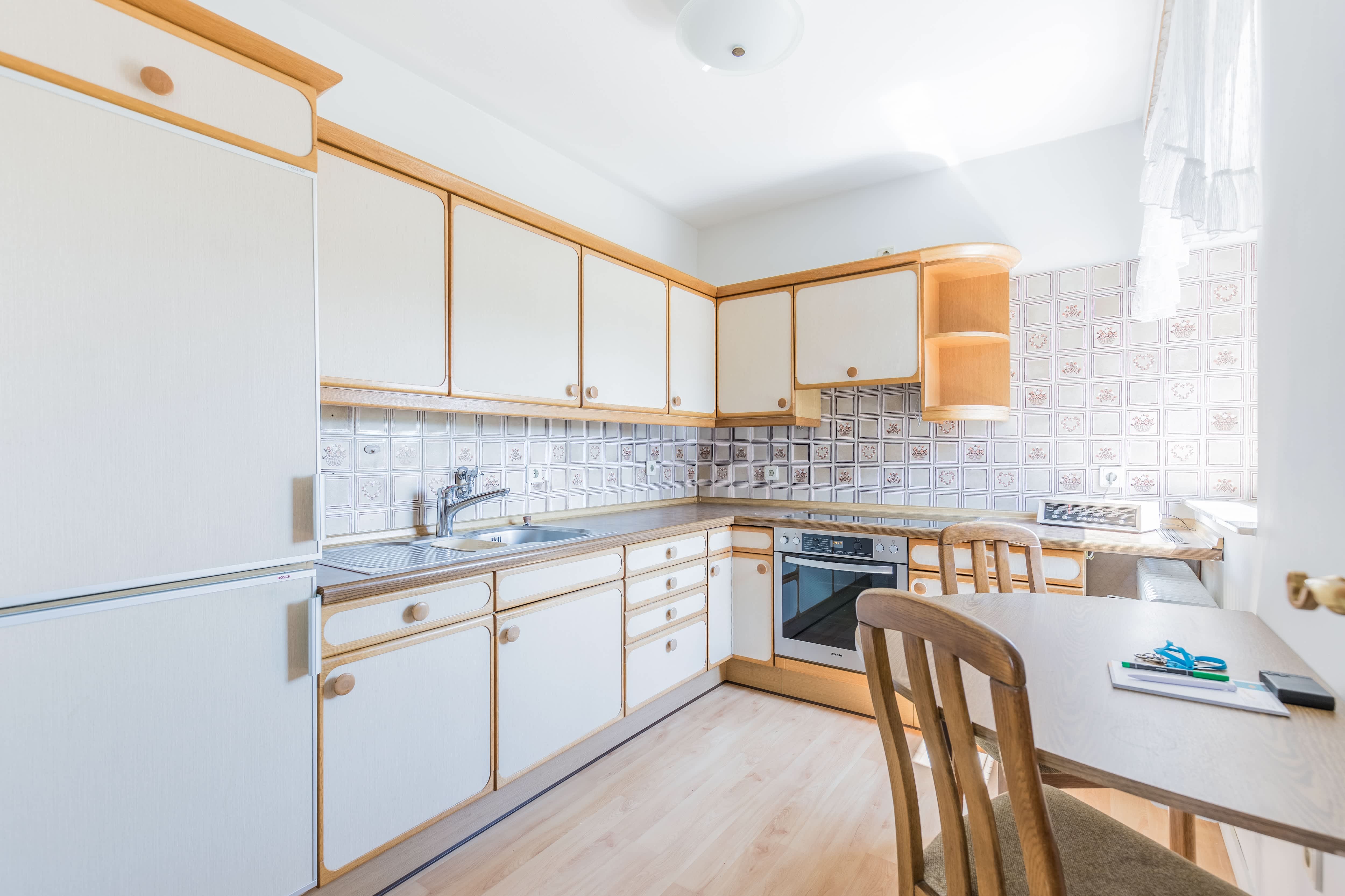 A white kitchen with a painted ceramic backsplash and wood accents