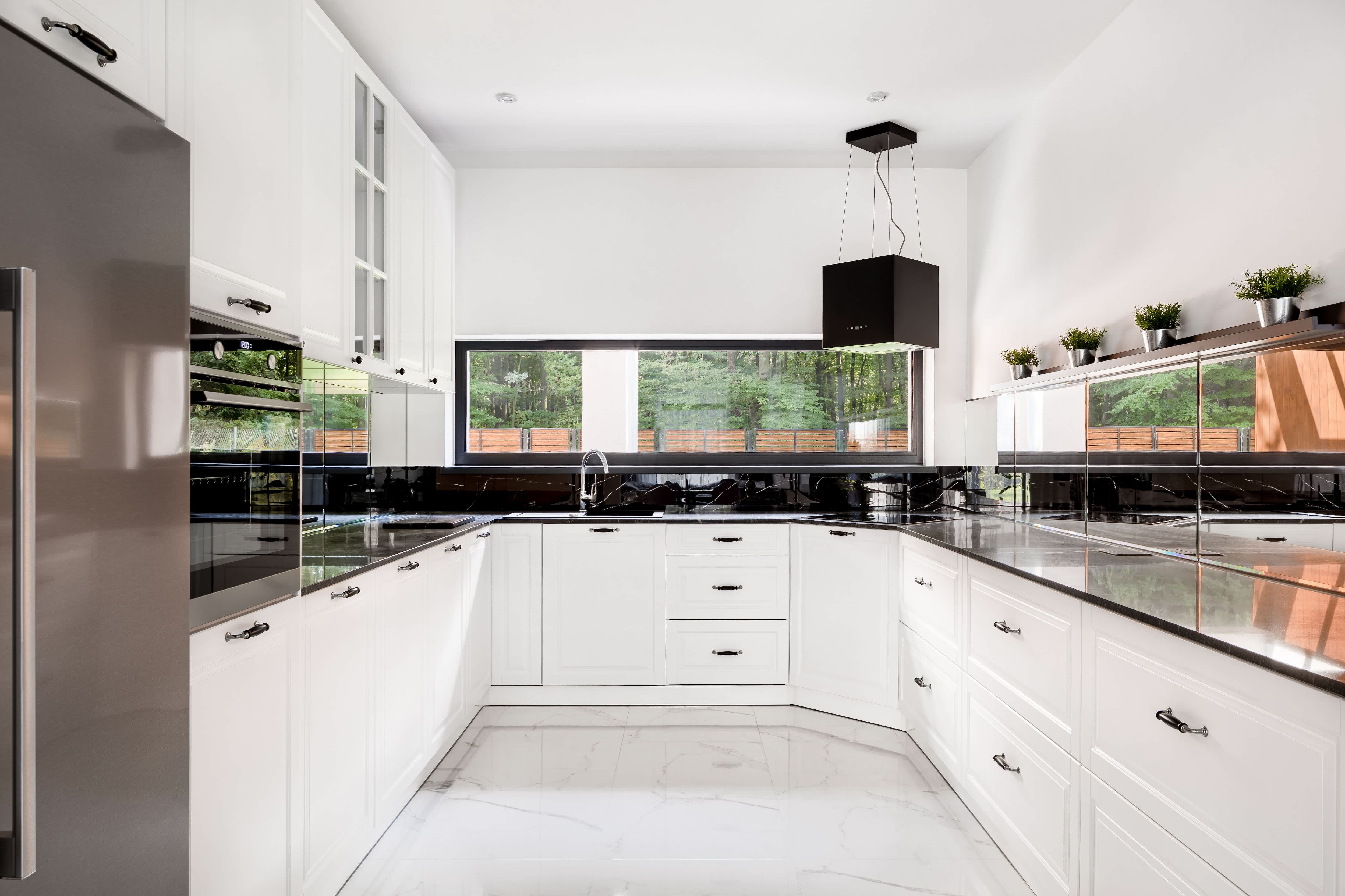 A modern black-and-white kitchen with a mirror backsplash