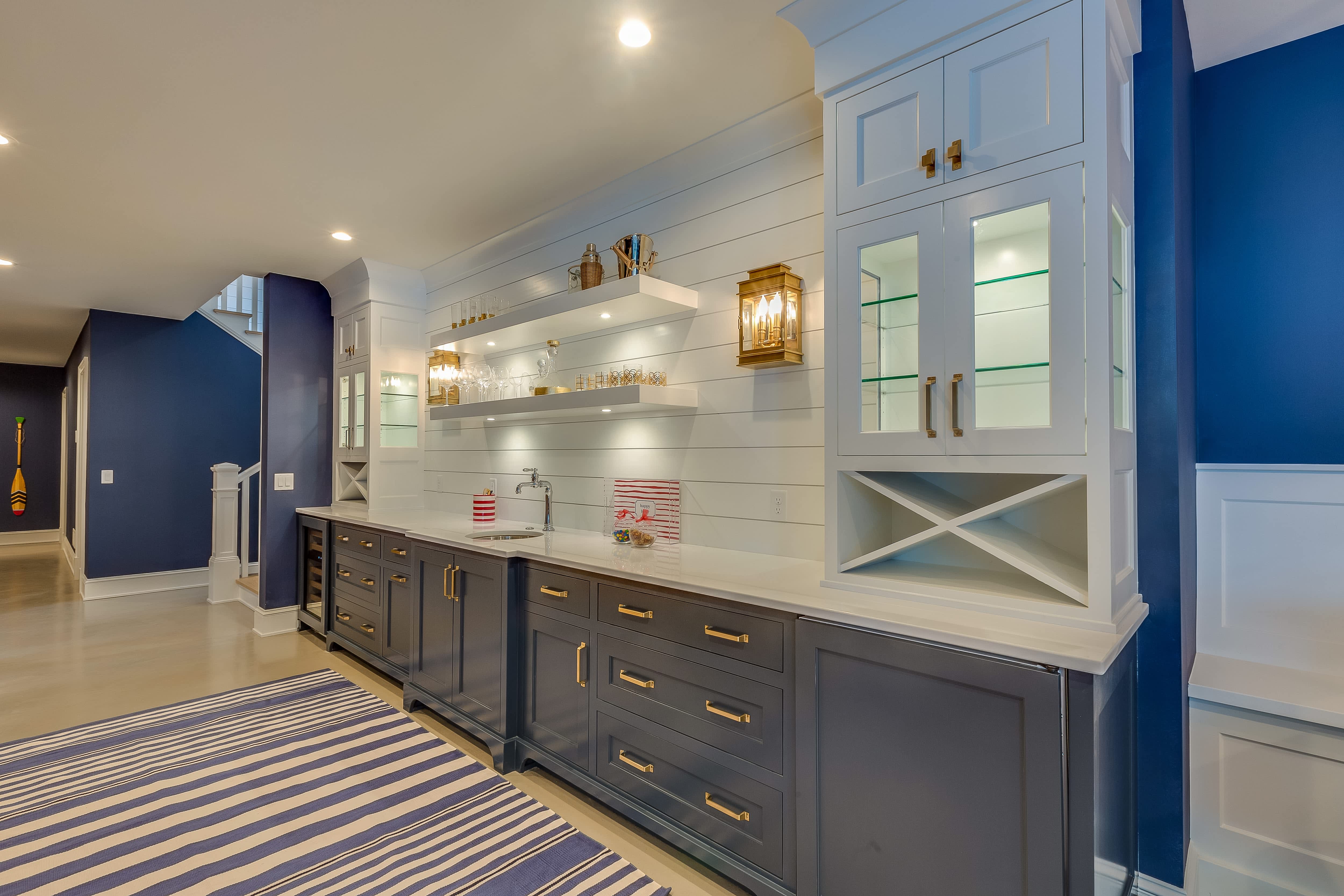 A kitchen with dark blue cabinetry, open shelving, and a shiplap backsplash