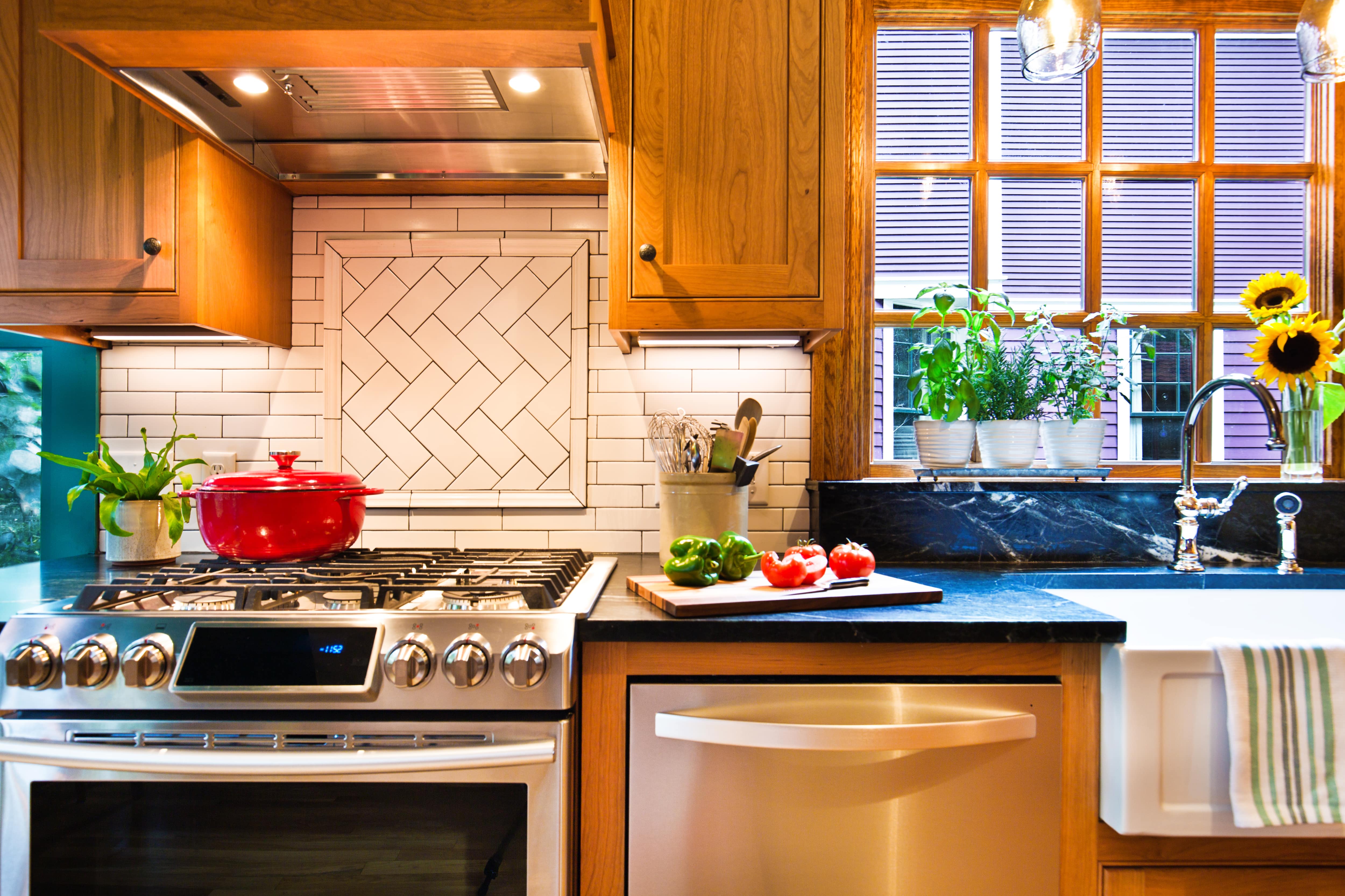 A kitchen with brown cabinets, white subway tile, and a herringbone picture frame