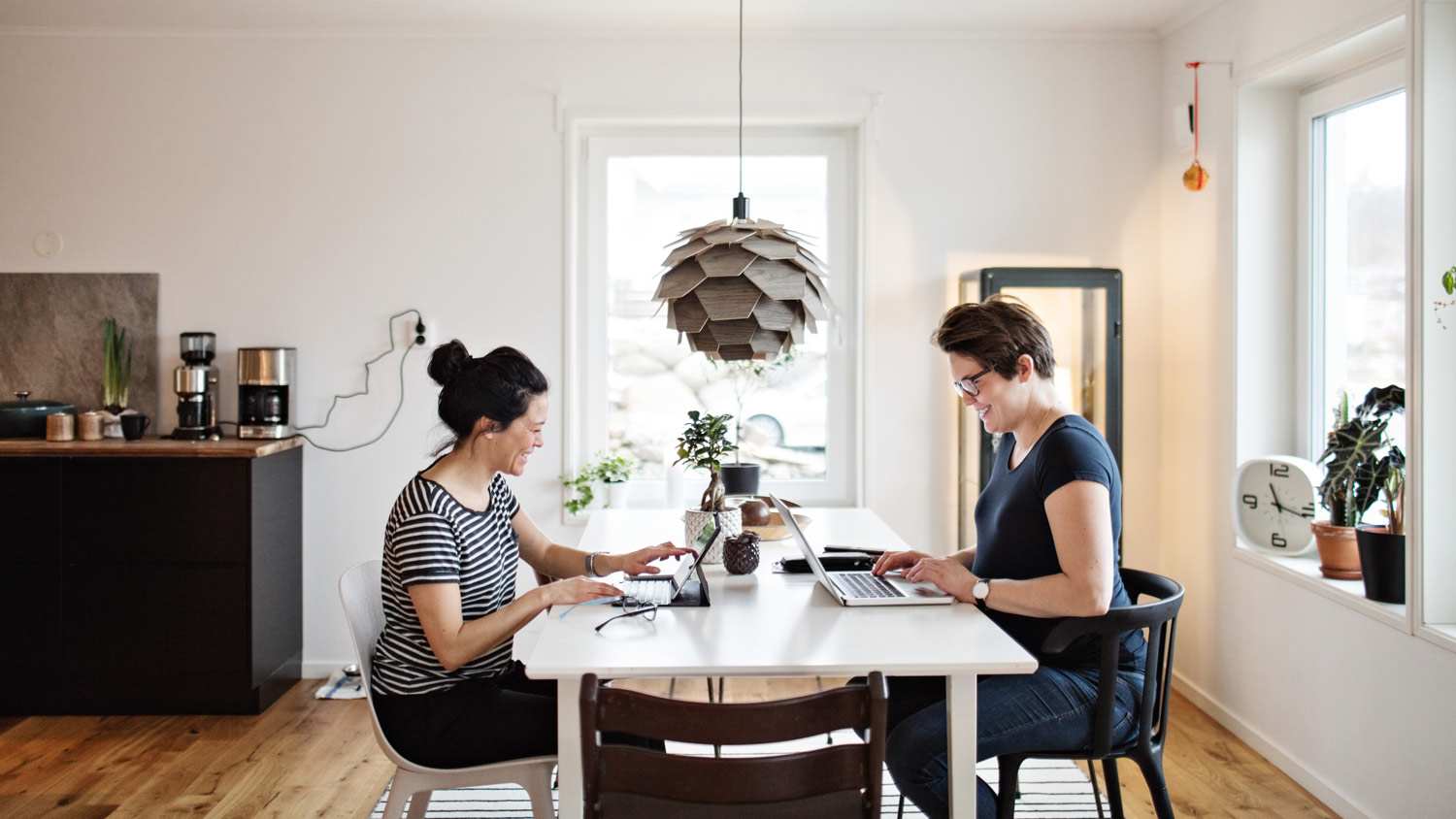 Two women working on their laptop at their living room table