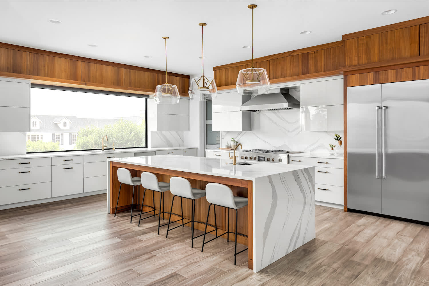 Kitchen with white marble backsplash, marble waterfall island and white cabinets