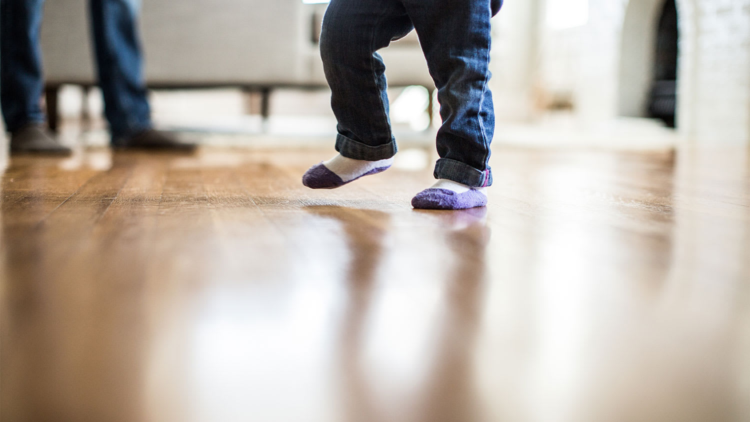 A closeup of a child walking on a wood floor