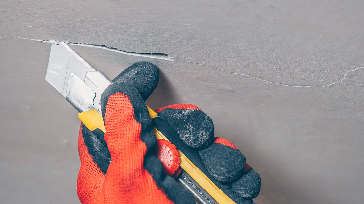 A closeup of a blade cutting into a ceiling crack