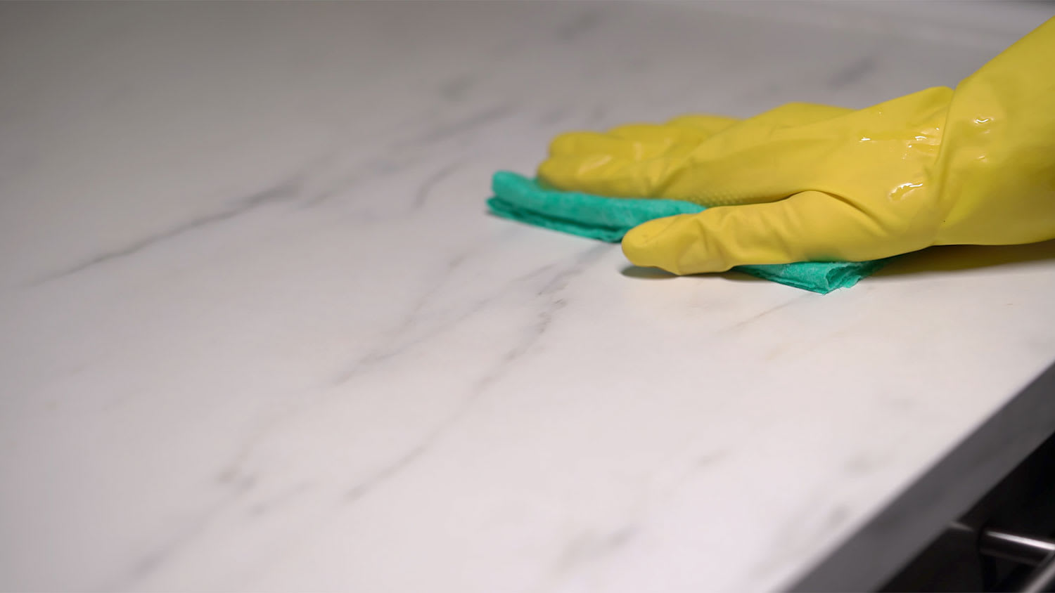 A hand wipes a marble countertop