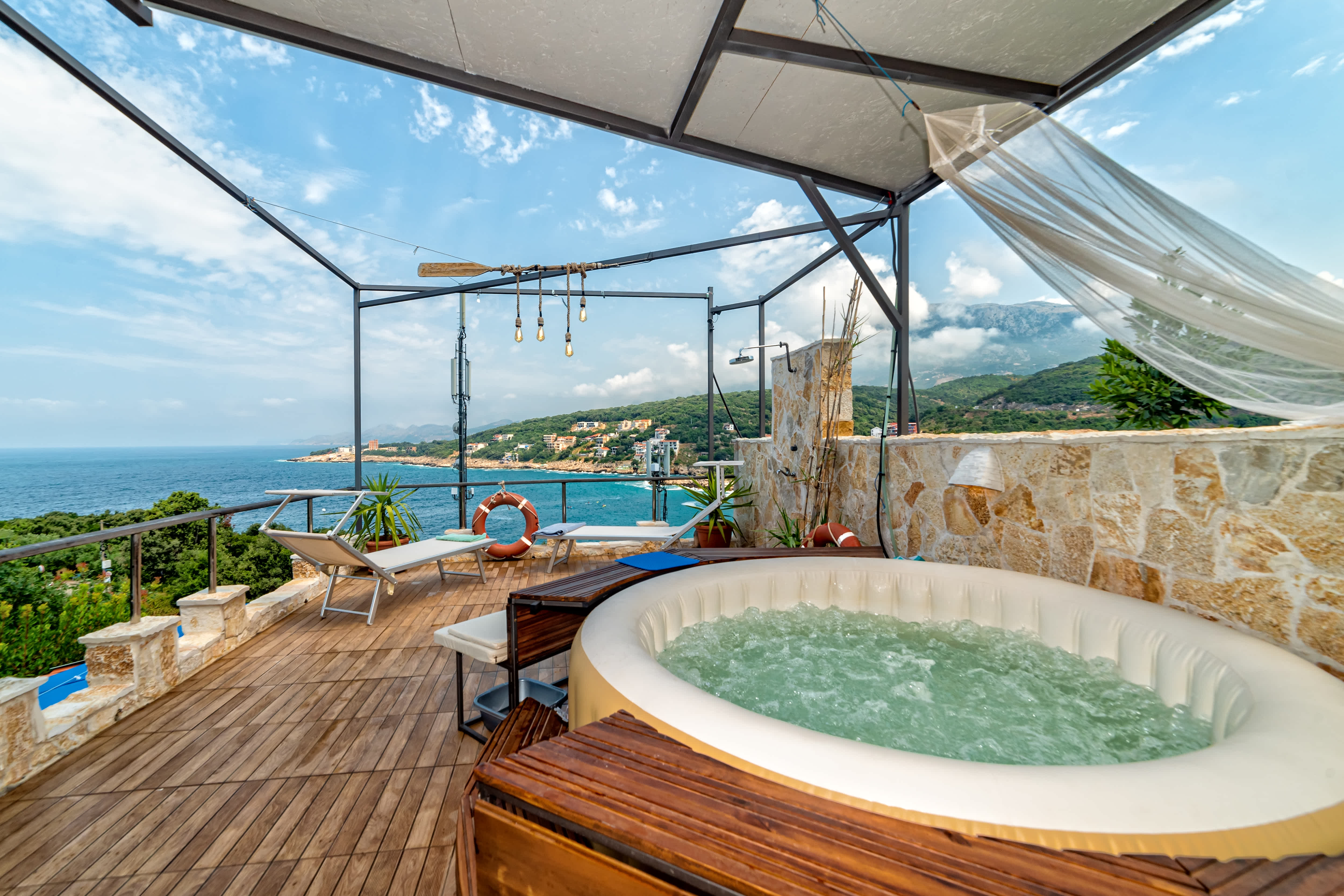 A deck overlooking an ocean with a small inflatable hot tub