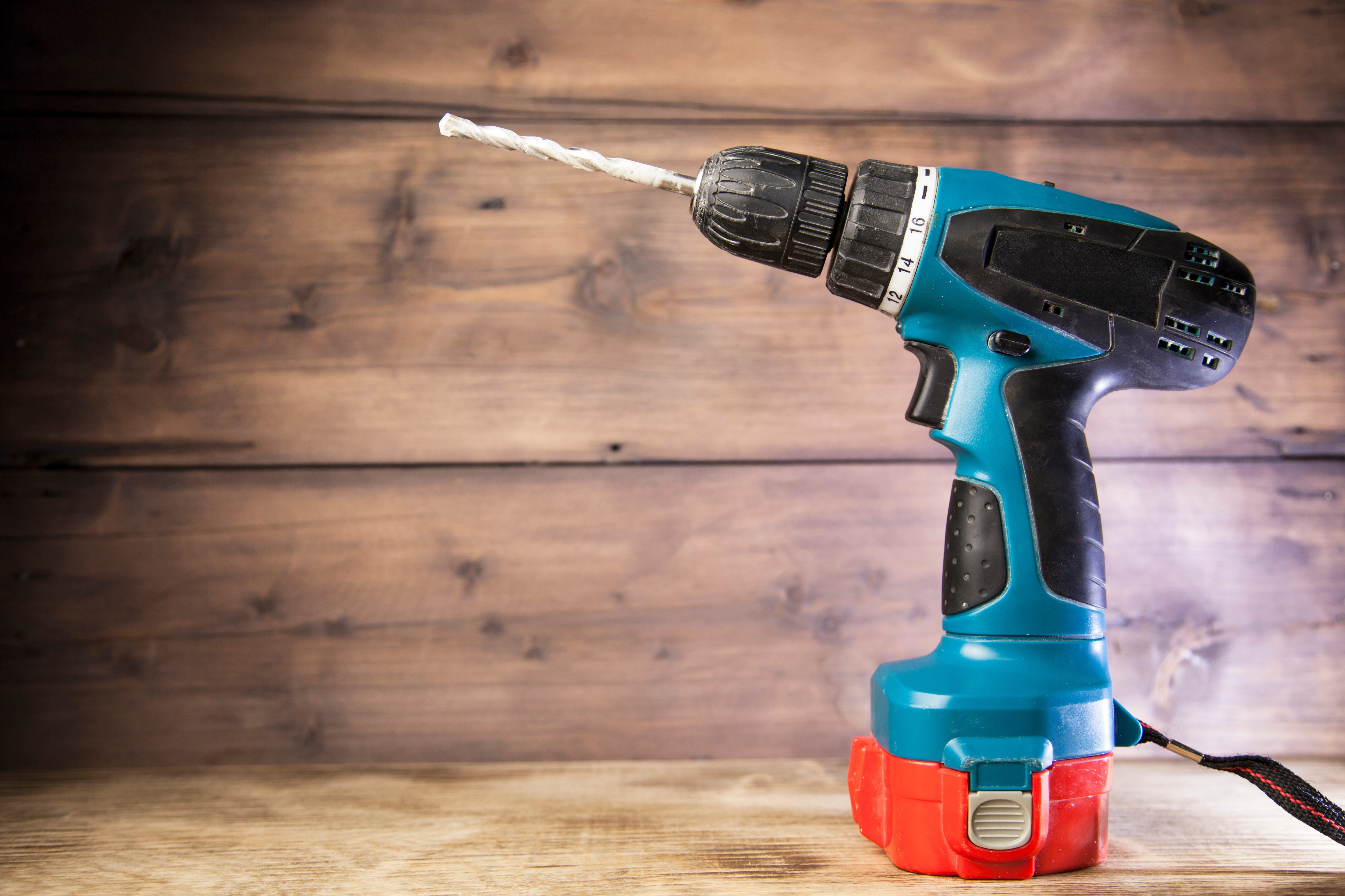Blue electric drill sitting on a wooden table