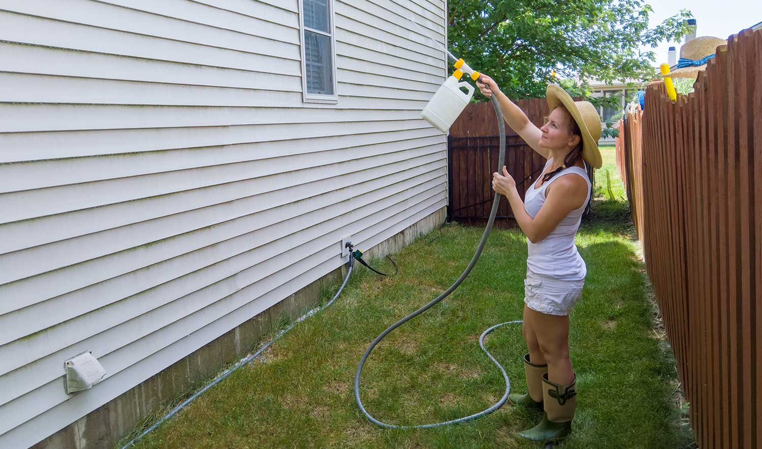 Woman spraying the siding on her house