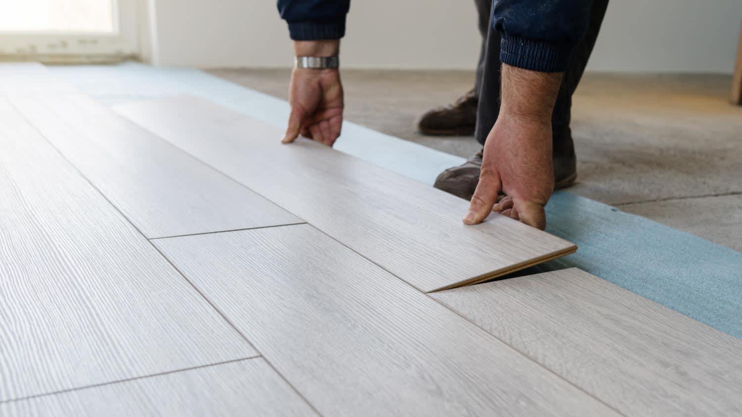 Worker installing new vinyl laminate floor tile
