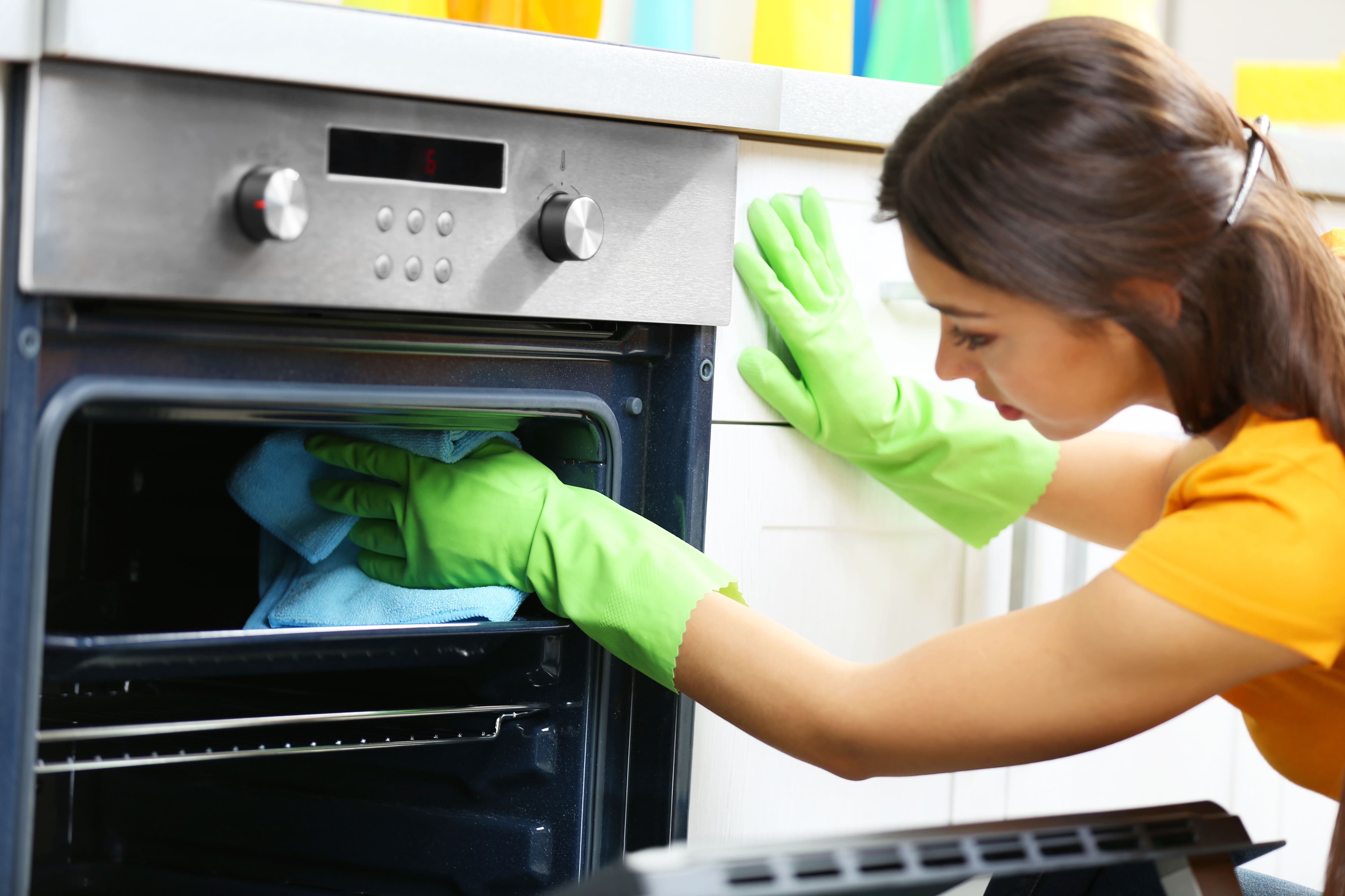 Women cleaning oven rack while wearing gloves