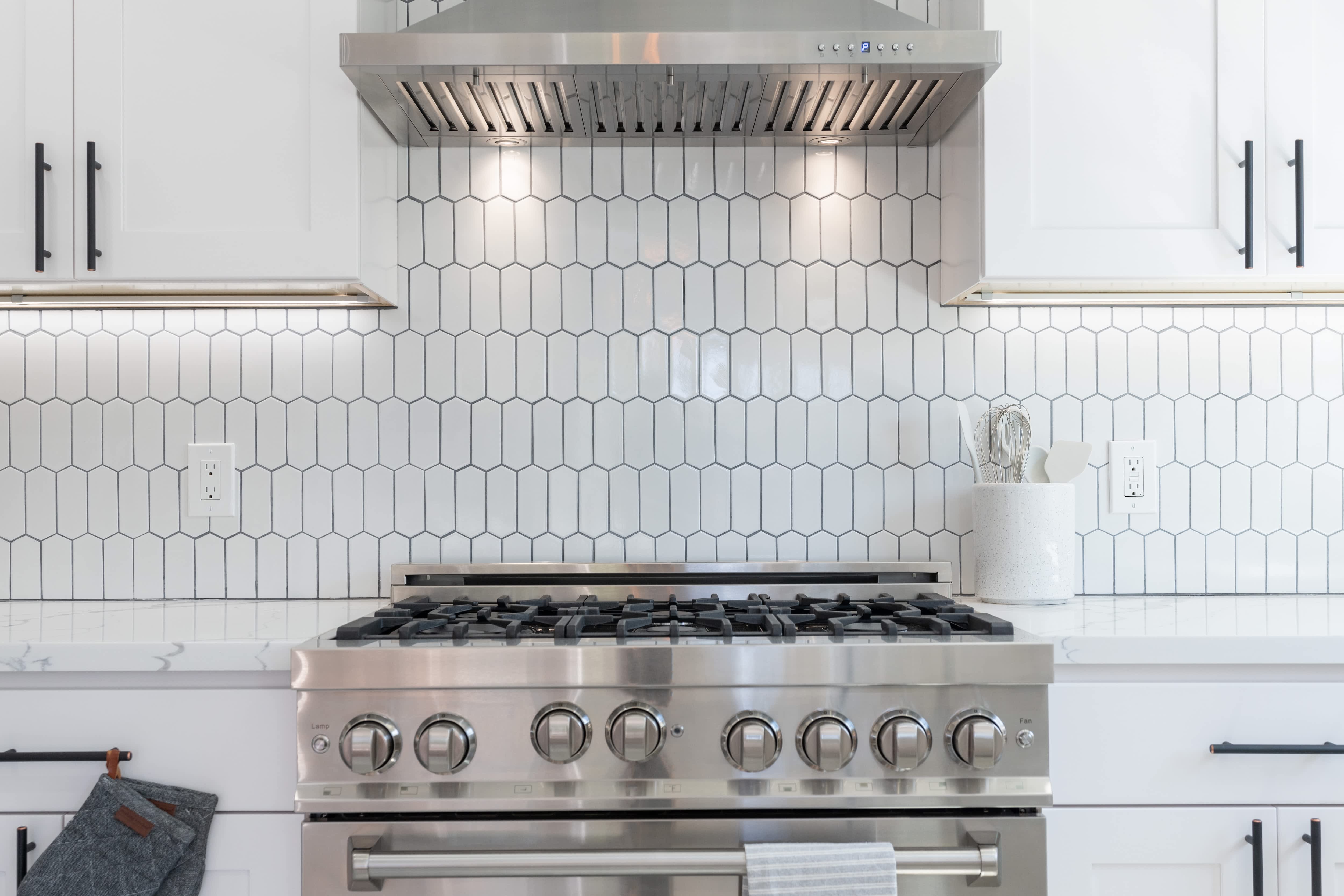 A modern white kitchen with white elongated hexagon backsplash