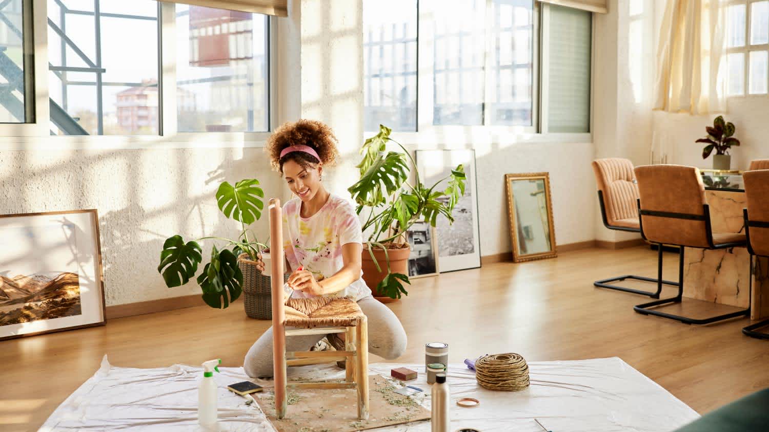 A woman painting a chair on a laminate floor