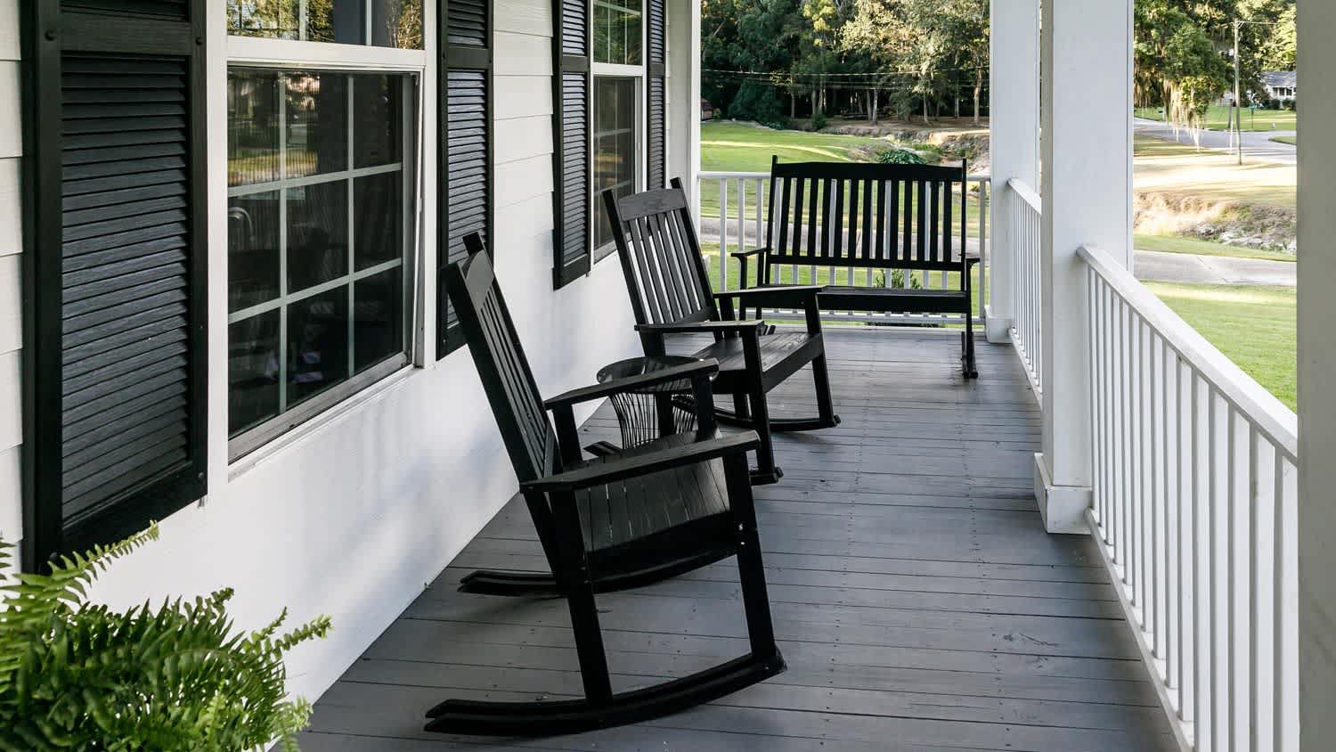 A black and white front porch with two rocking chairs, including different tones of black paint