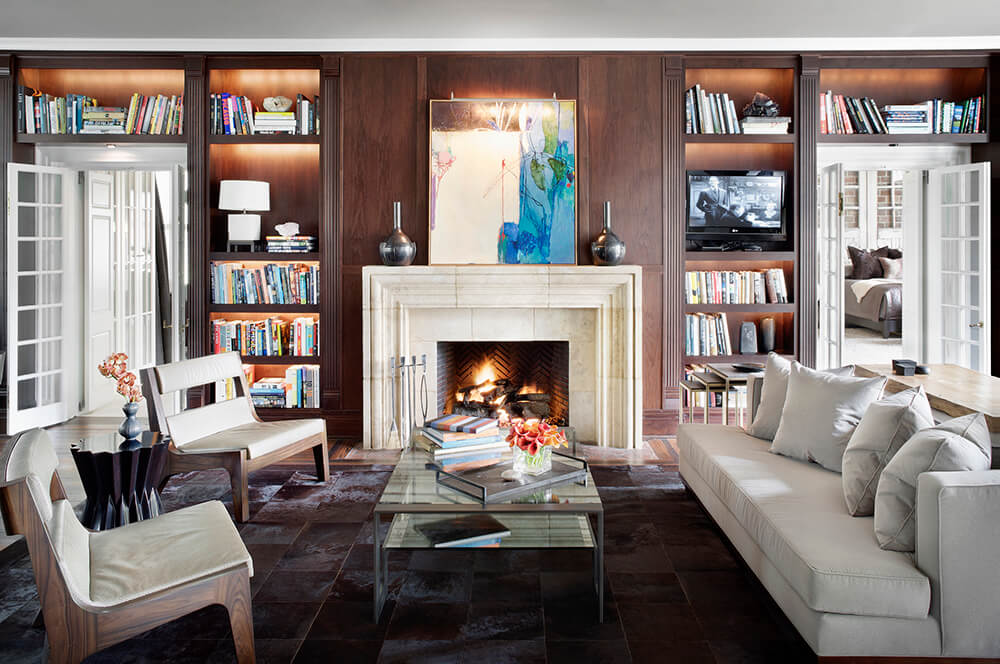 Library sitting room with built-in bookcases and a white fireplace