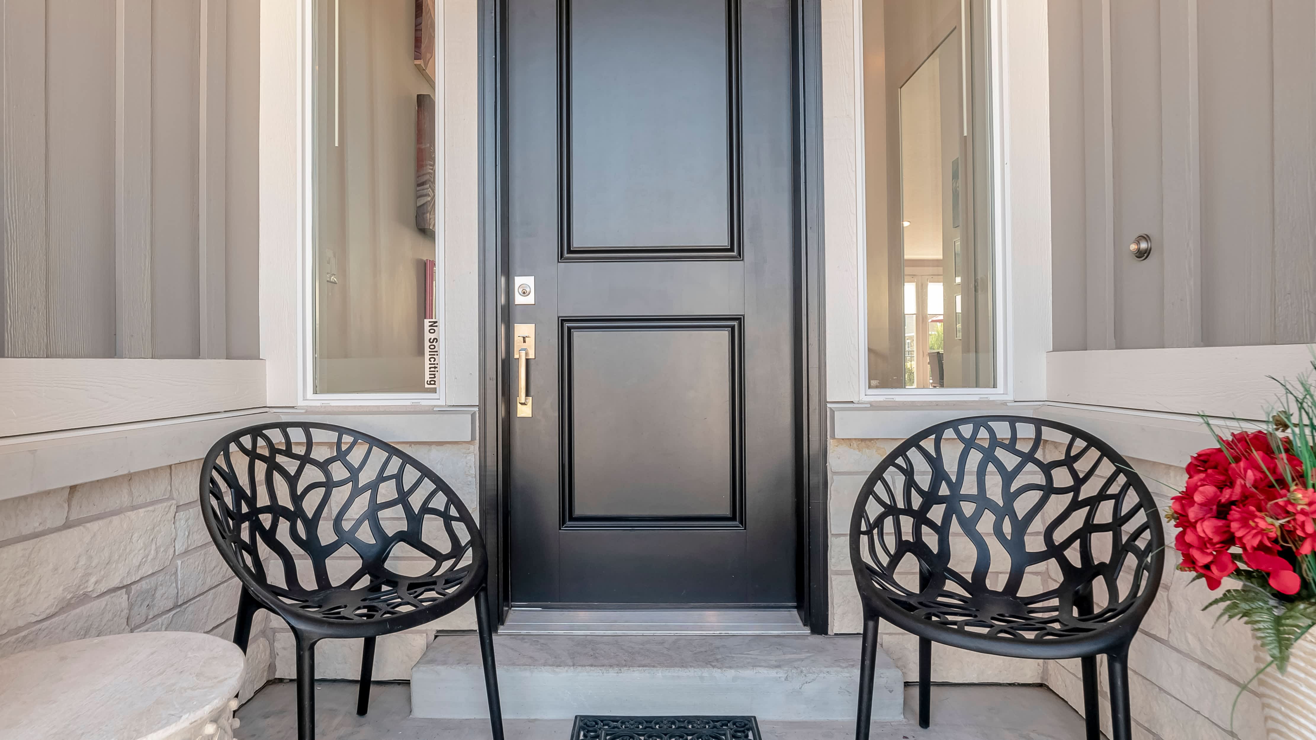 Front porch with black entryway door and black outdoor accent chairs
