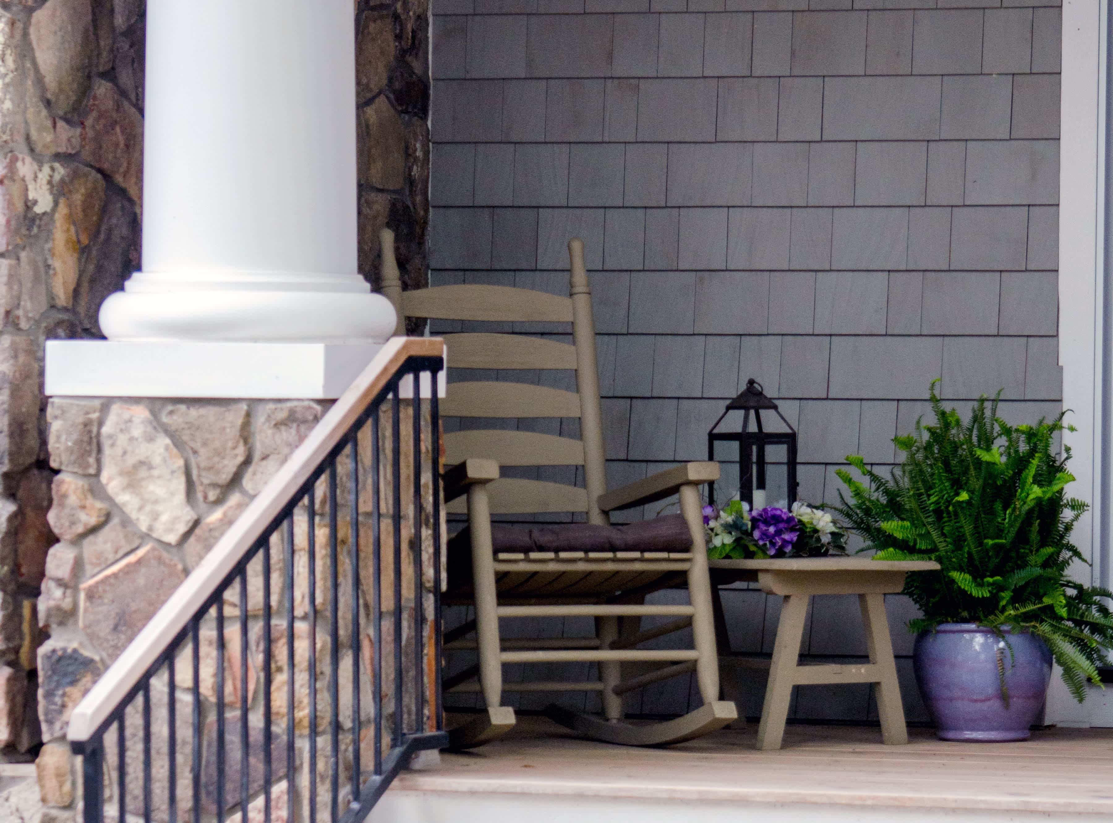 Beige rocking chair on front porch next to planter