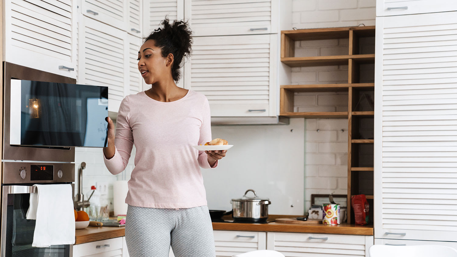 A woman uses a microwave