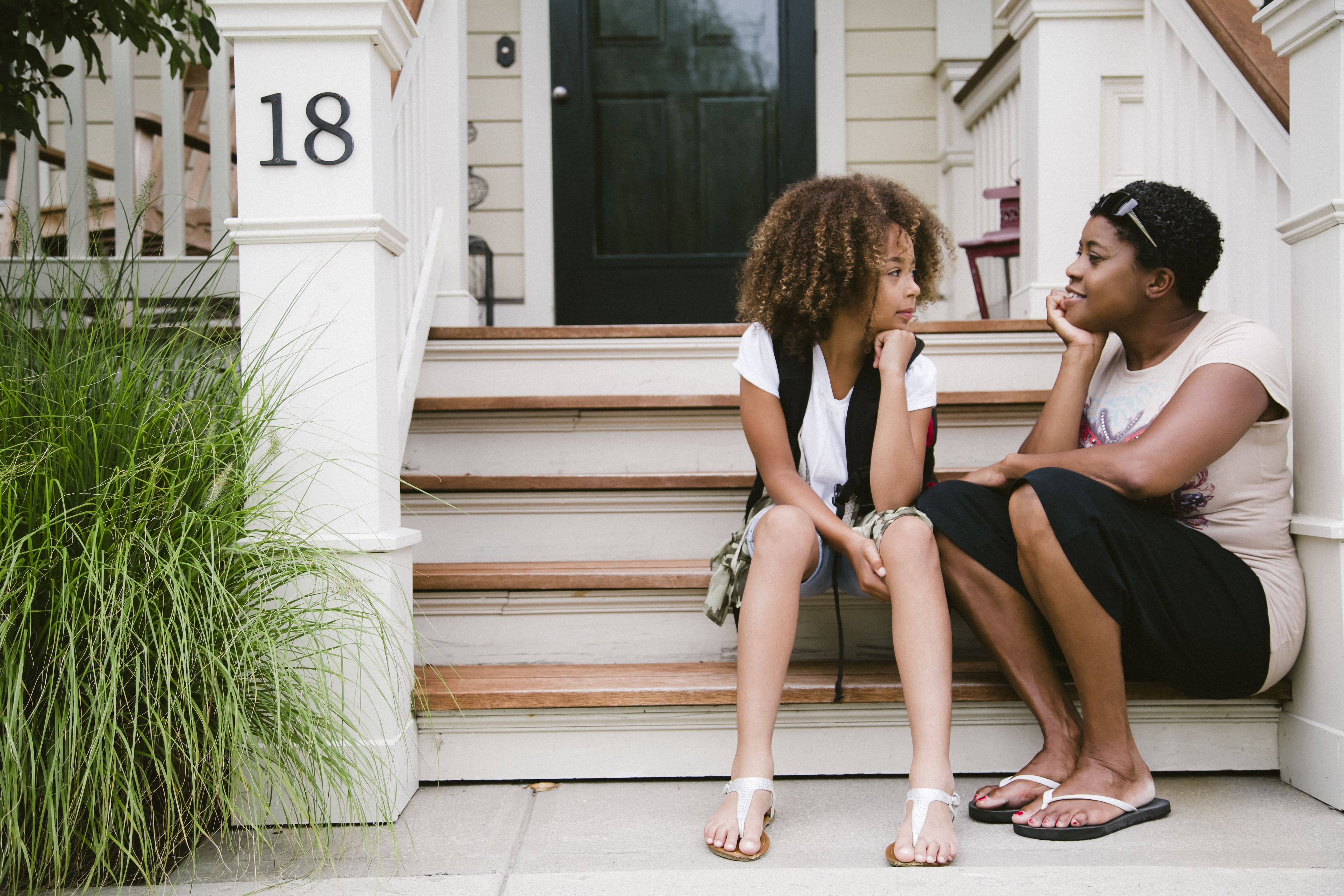 Mother and daughter sitting on front porch talking