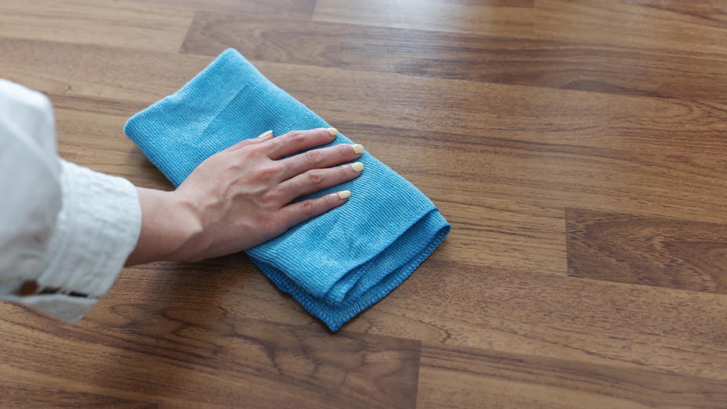 A woman wiping a laminate flooring with a cloth