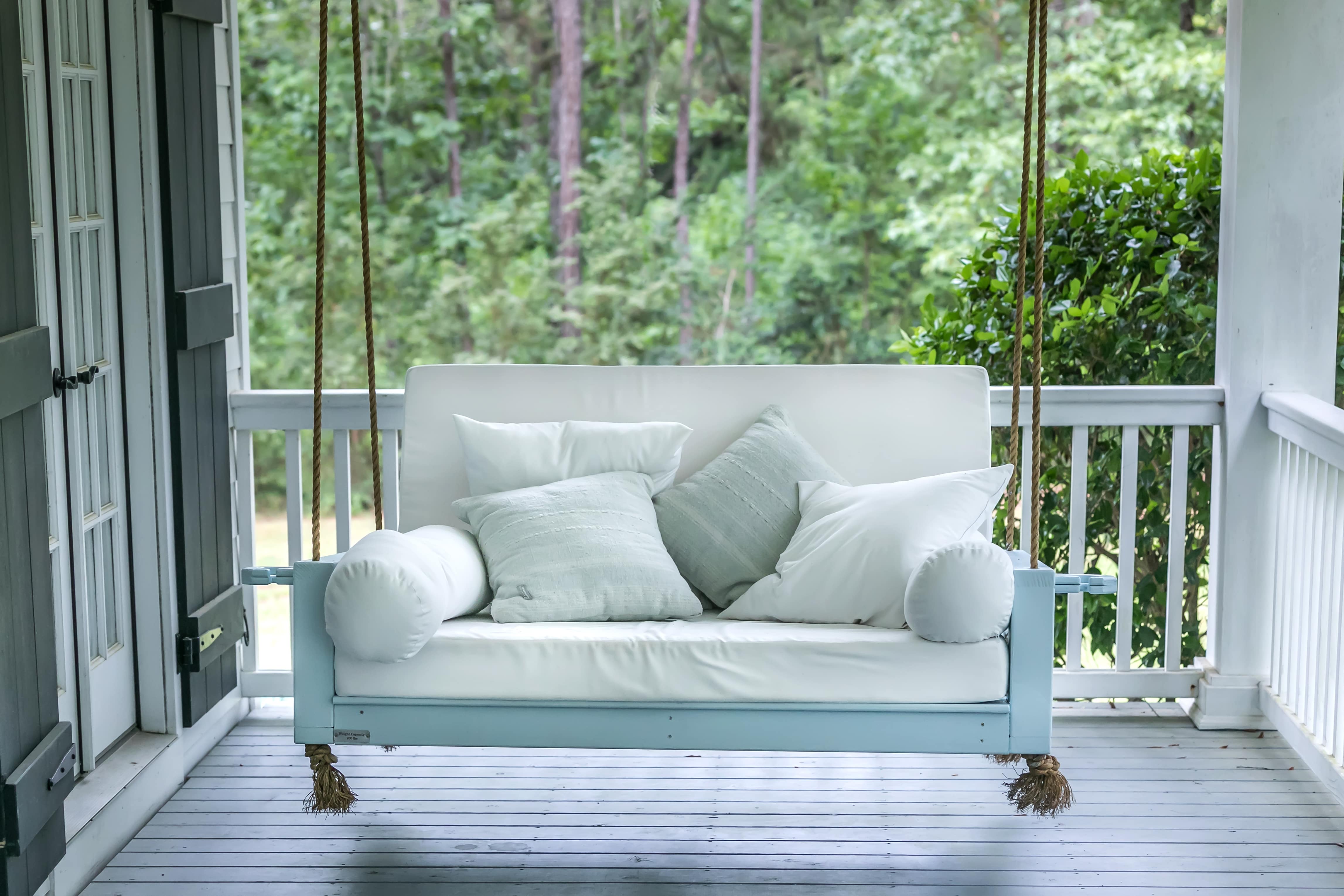 White front porch swing with teal blue throw pillows