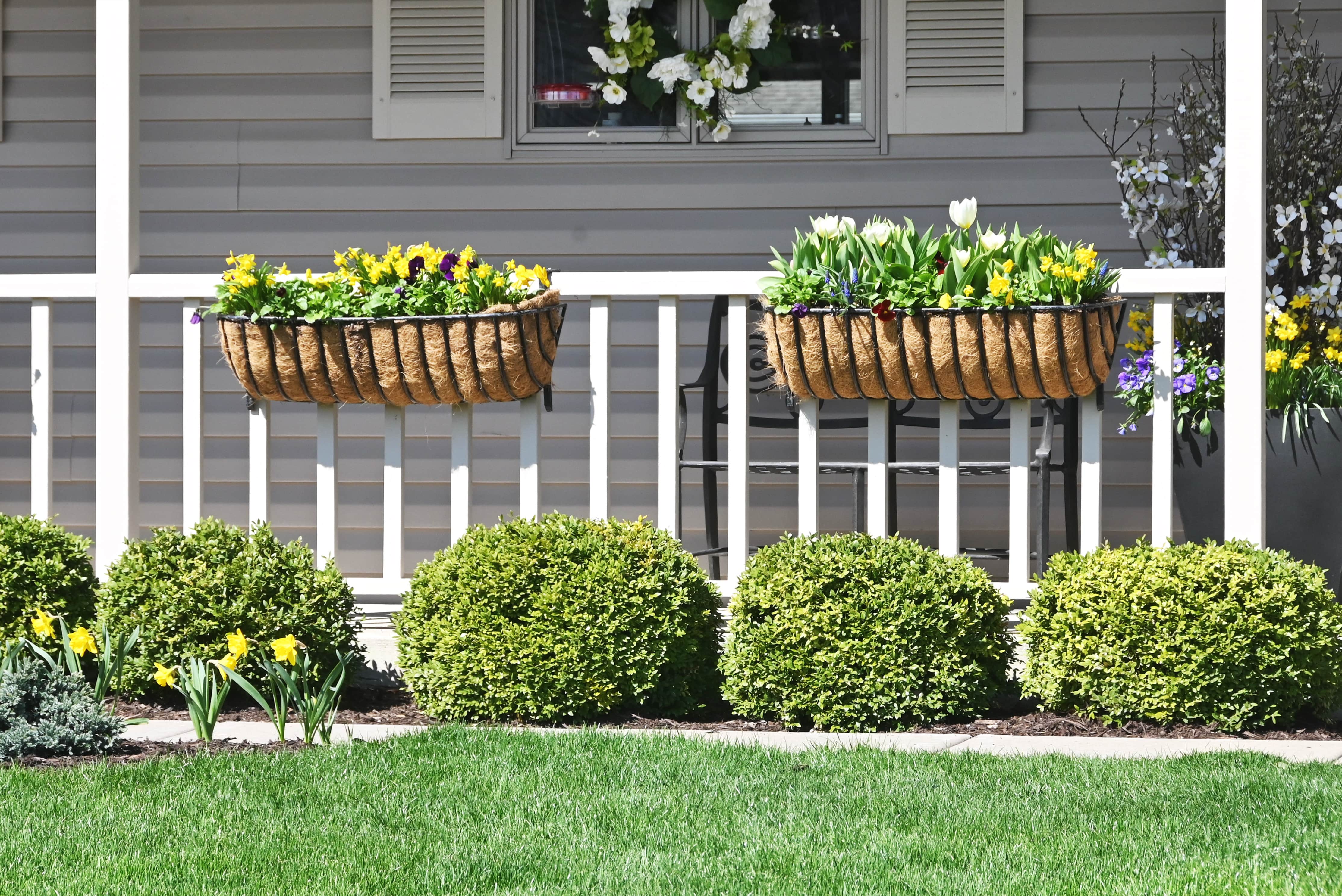Flower planters hung on front porch railing