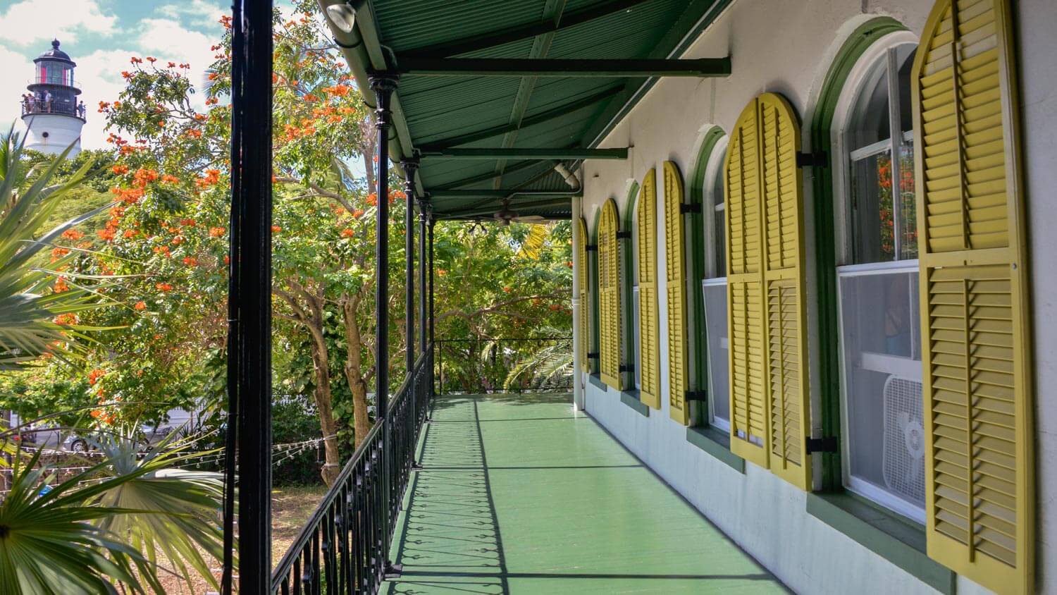 A dark green porch with yellow shutters, including different tones of dark green paint