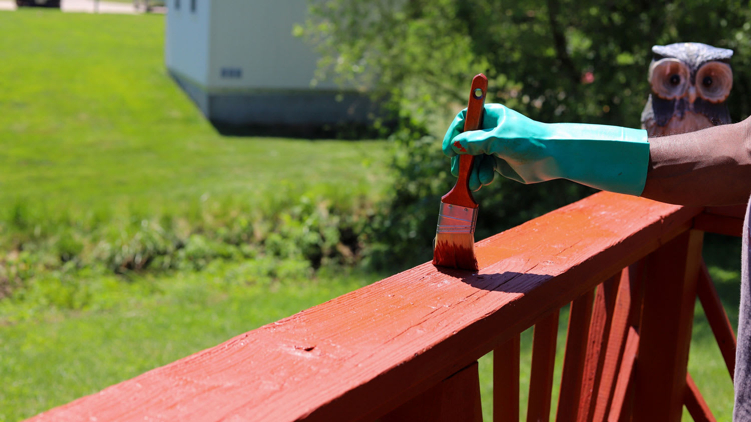 A man painting red a deck railing