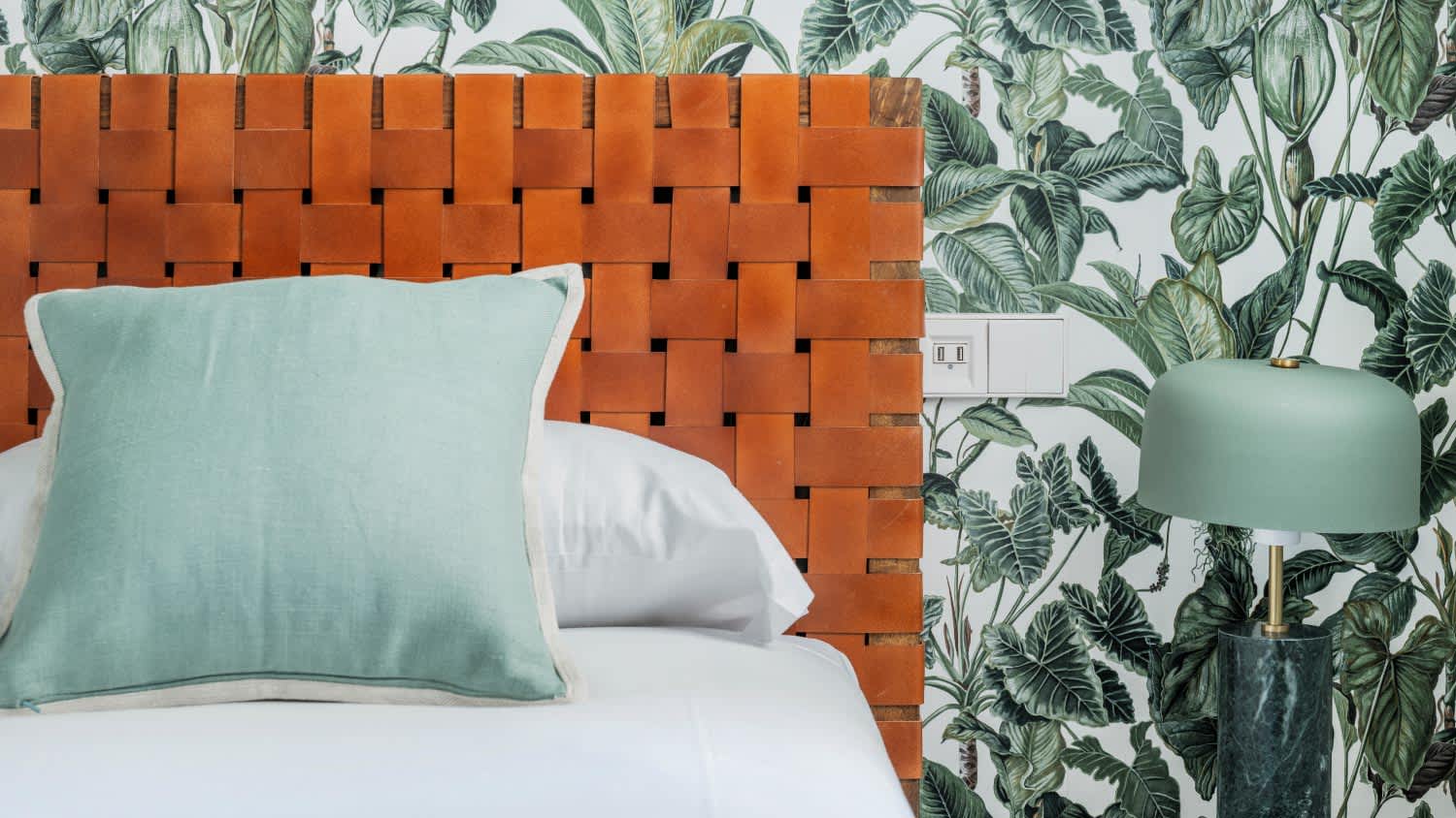 A bedroom with leather headboard and decorative wallpaper