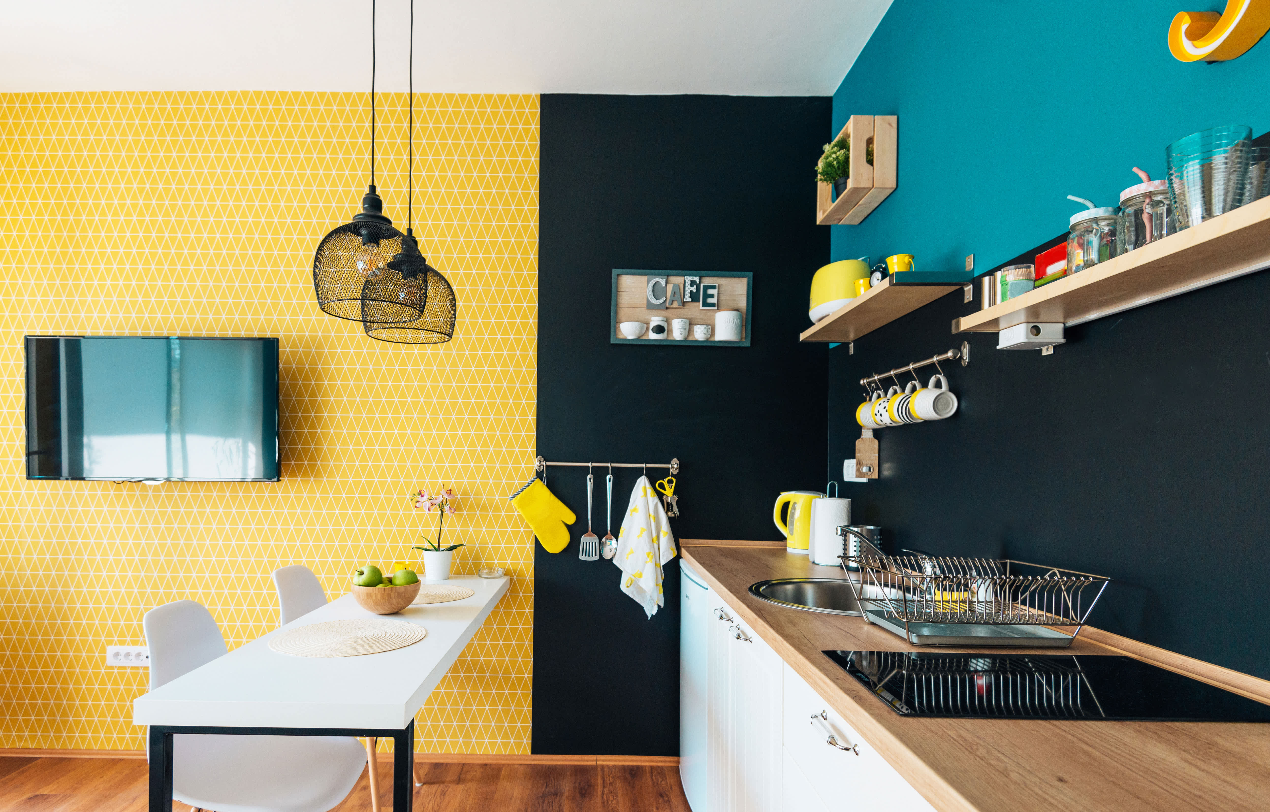 A small black kitchen with a yellow accent wall