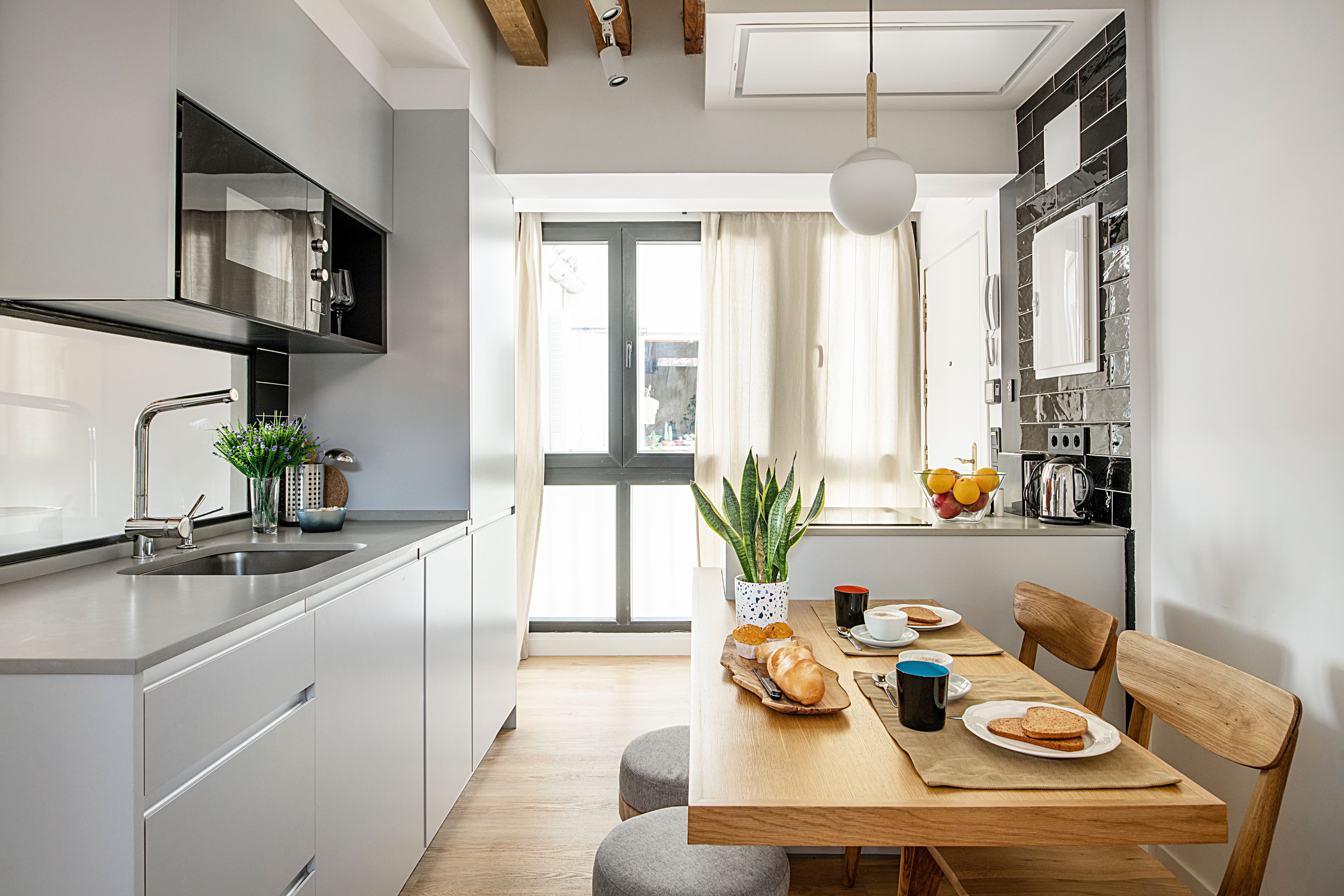 A galley kitchen with tiny table and stool that nestle underneath