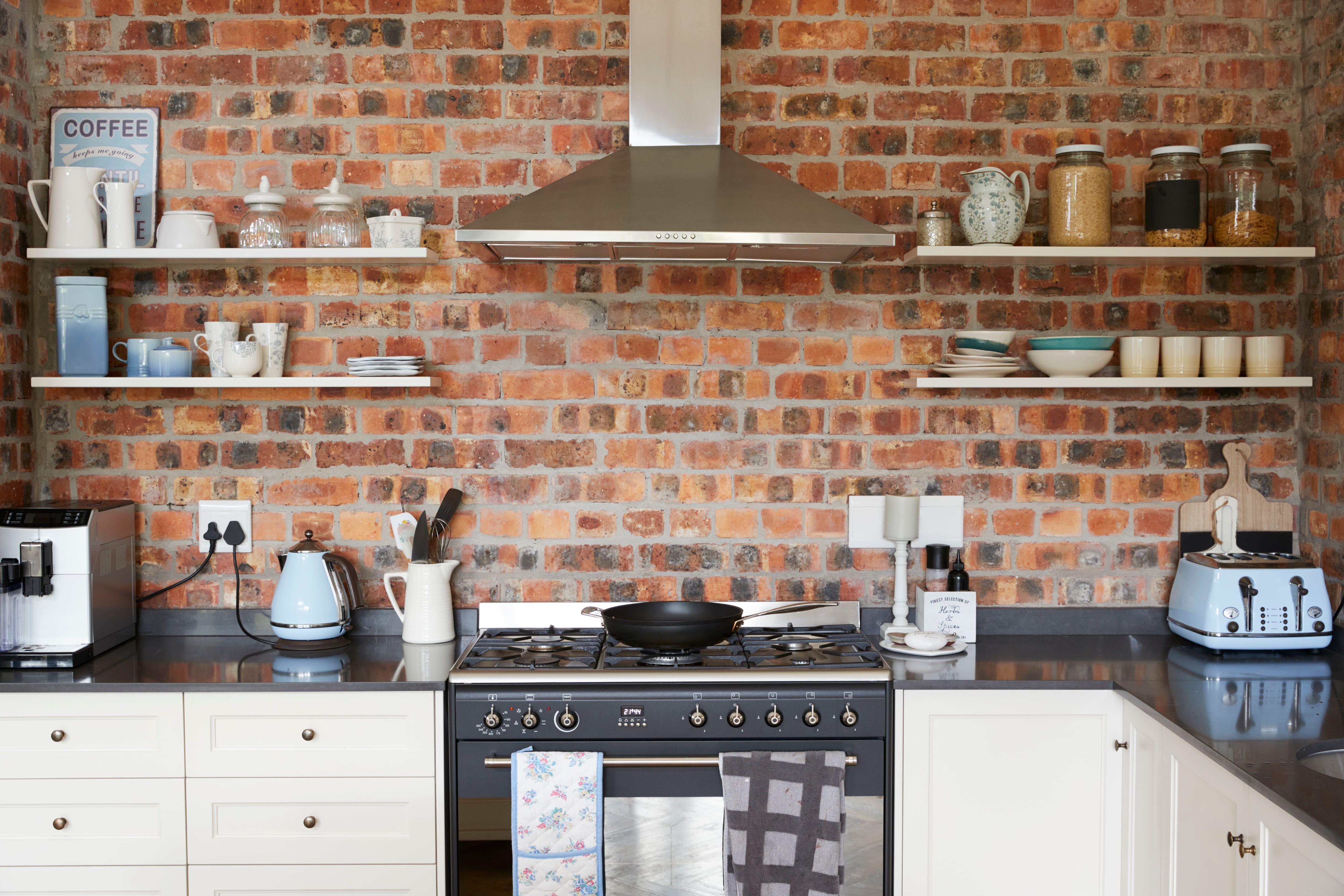 Kitchen floating shelves on a brick wall displaying organized dishes