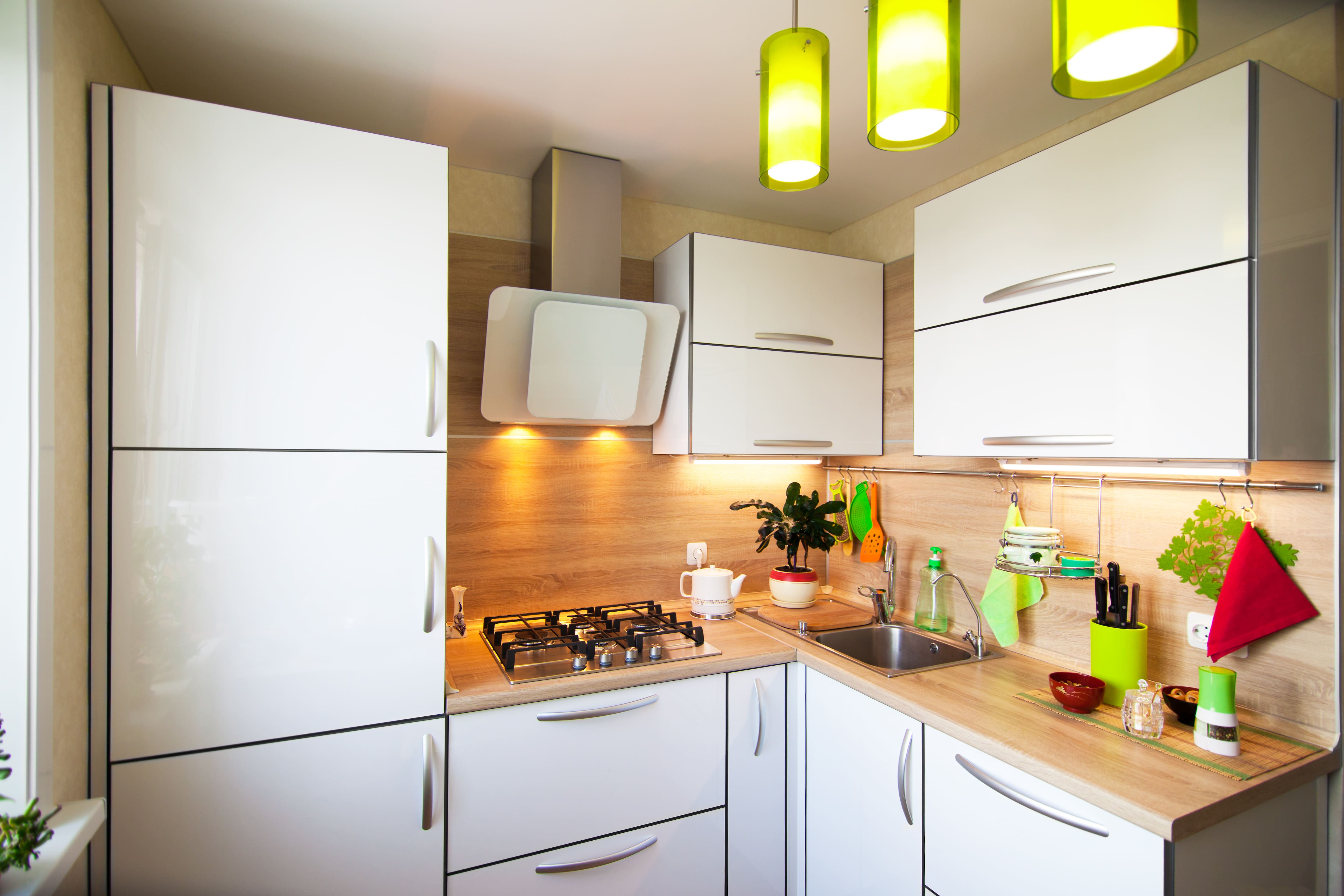 A small white and brown kitchen with green pendant lights