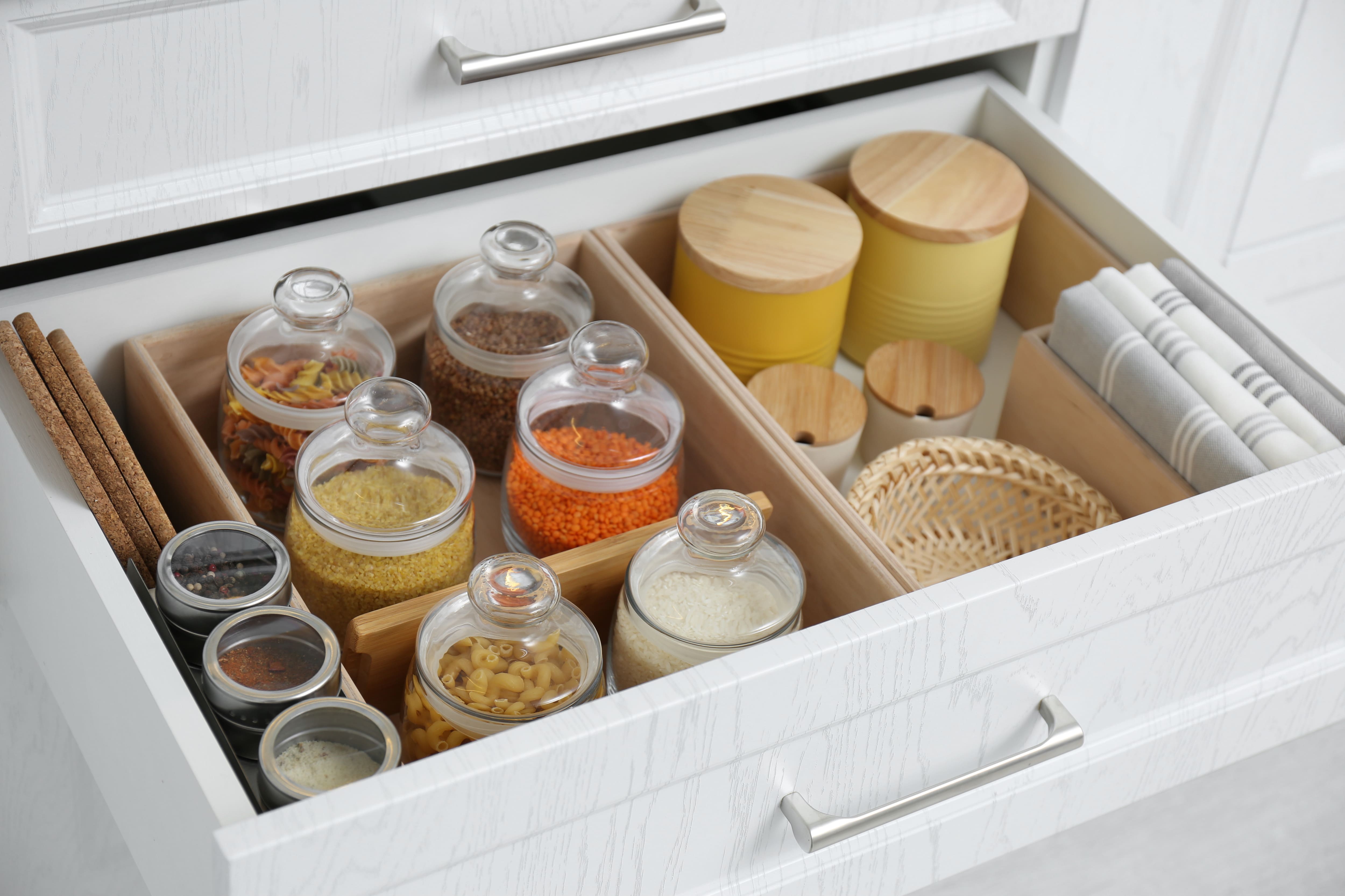 An open pantry drawer with jars of spices and drawer dividers